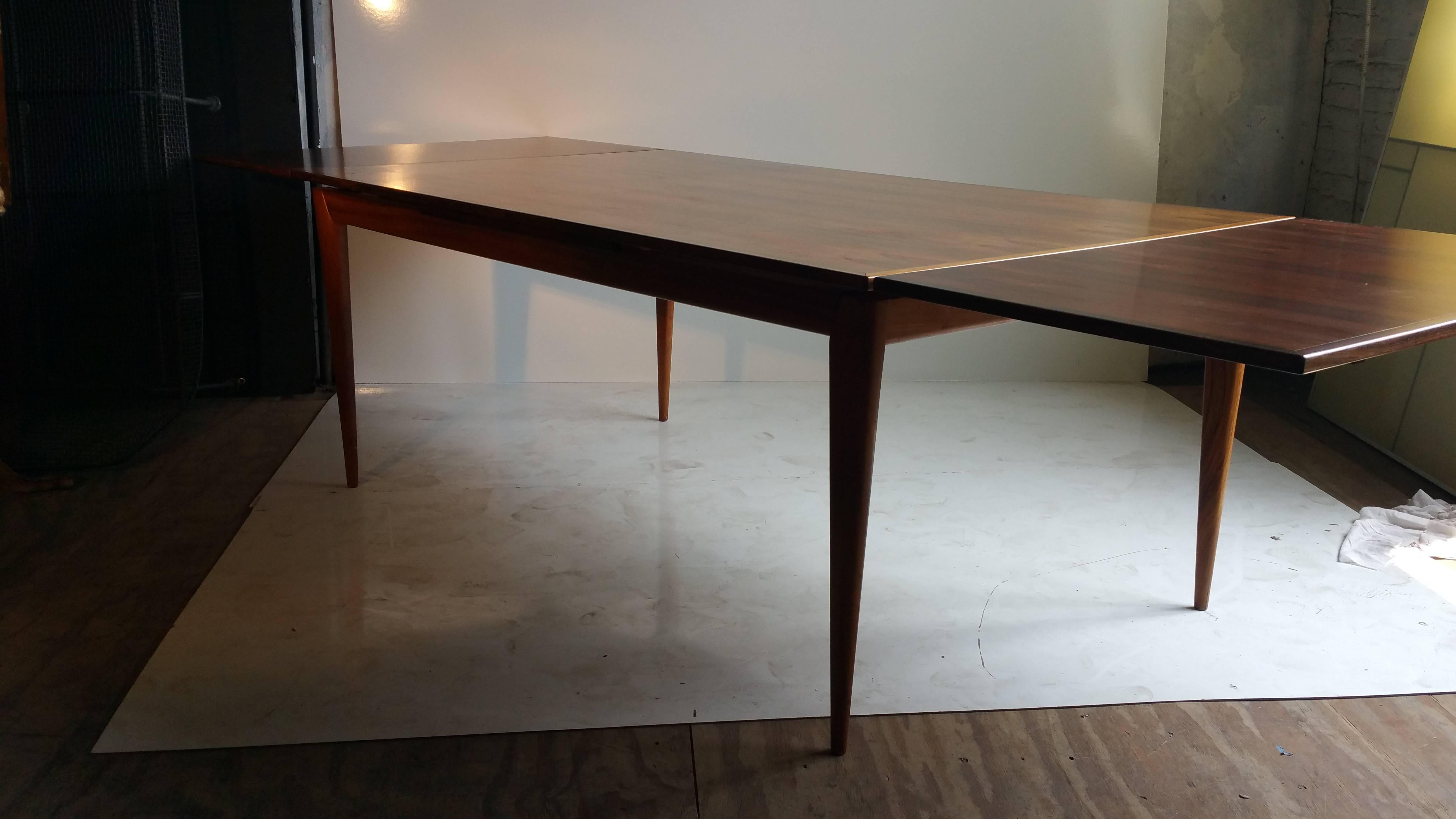 Danish modern rectangular draw leaf dining table will make a fantastic addition to any modern dining room. This 'Model 9' table was designed by Niels Otto Møller for J.L. Møller. Crafted in Brazilian rosewood, this piece features bookmatched rich