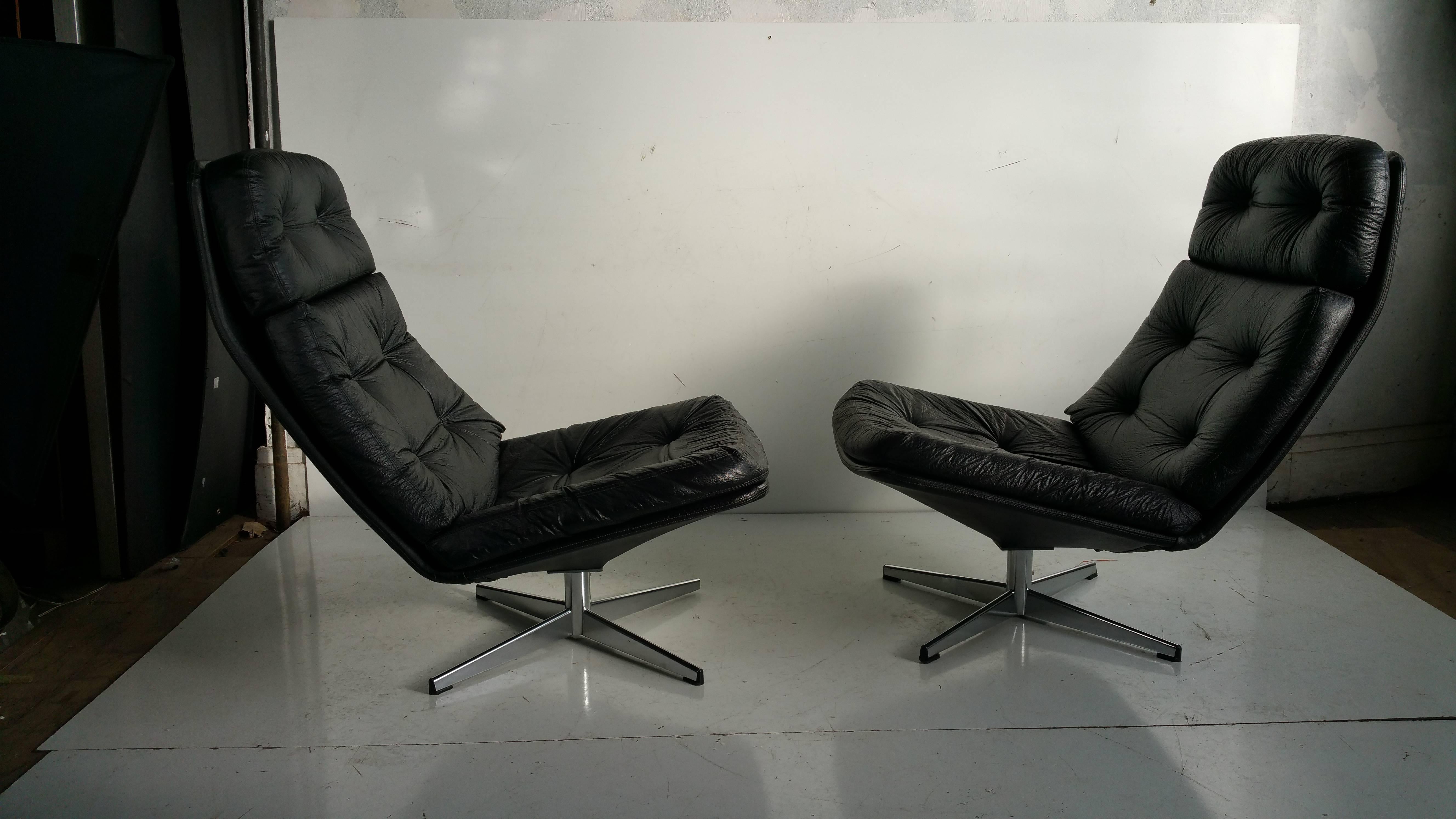  Pair of Mid Century Modern lounge chairs by Overman Unusual form,. Black crackle vinyl upholstery with removable cushions and chrome swivel bases which offer a modern space age look and extremely comfortable seating ..