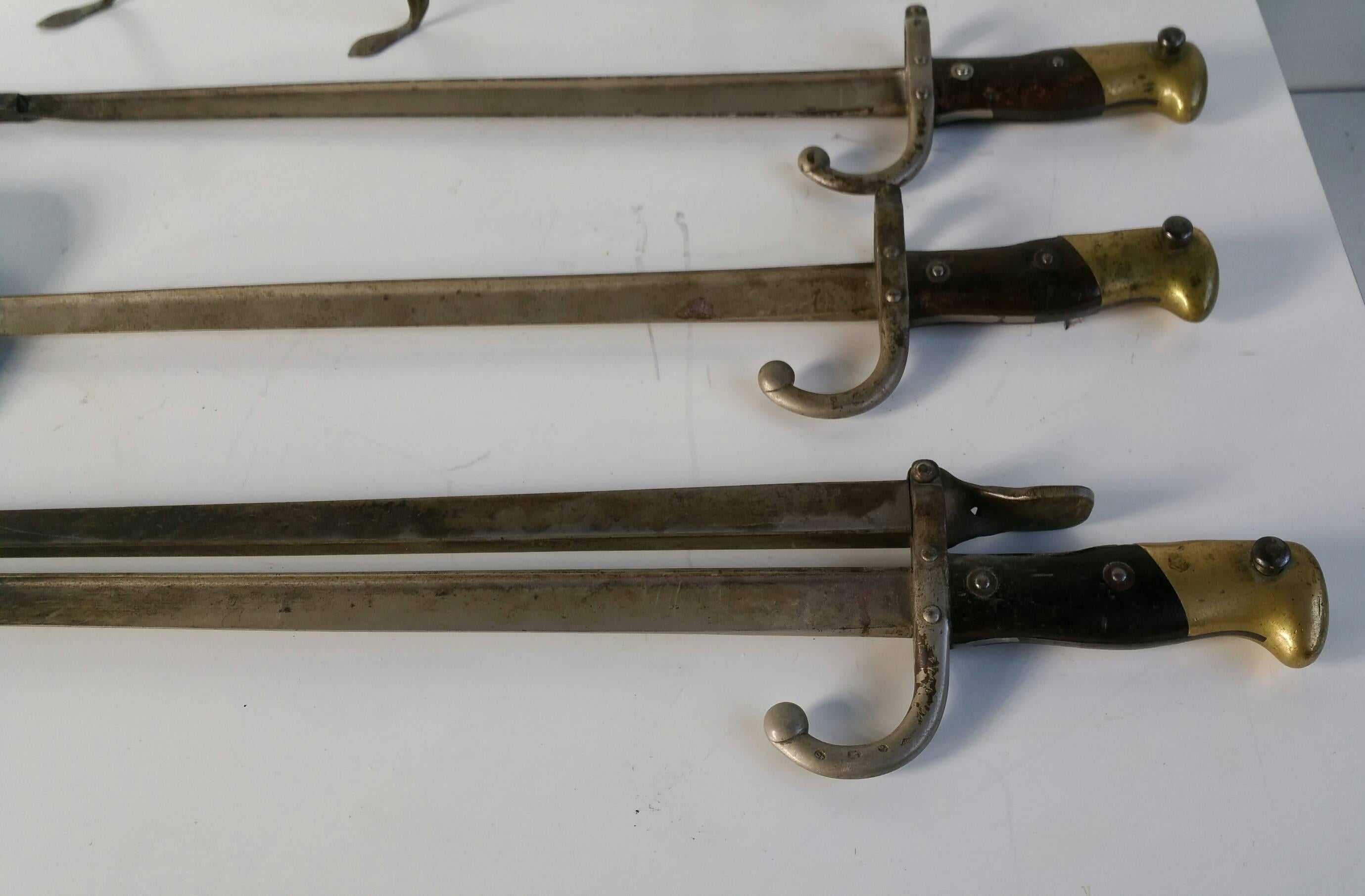 A SET OF THREE FRENCH STEEL 'BAYONET' FIRE-TOOLS AND ANDIRONS
LATE 19TH CENTURY 
The blades with various engraved numbers and stamps 
The shovel: 26½ in. 