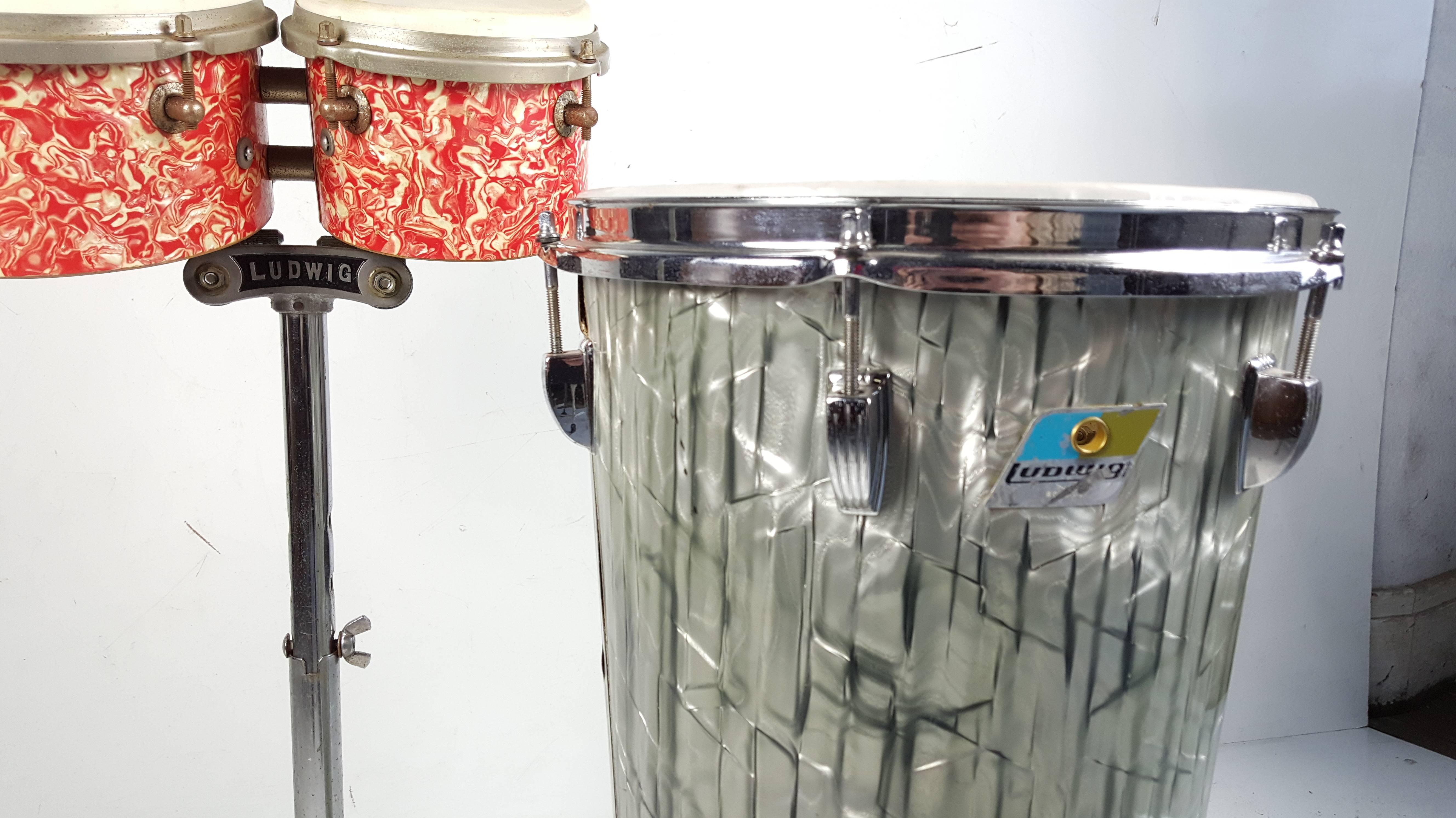 Interesting group of vintage Ludwig drums,, 1950s bongo drums,, retain original stand with early LUDWIG cast steel,period red-orange marbelized finish,, Conical modernist 1970s conga drum,,classic Beatles laminate over wood shell,,Professional drums