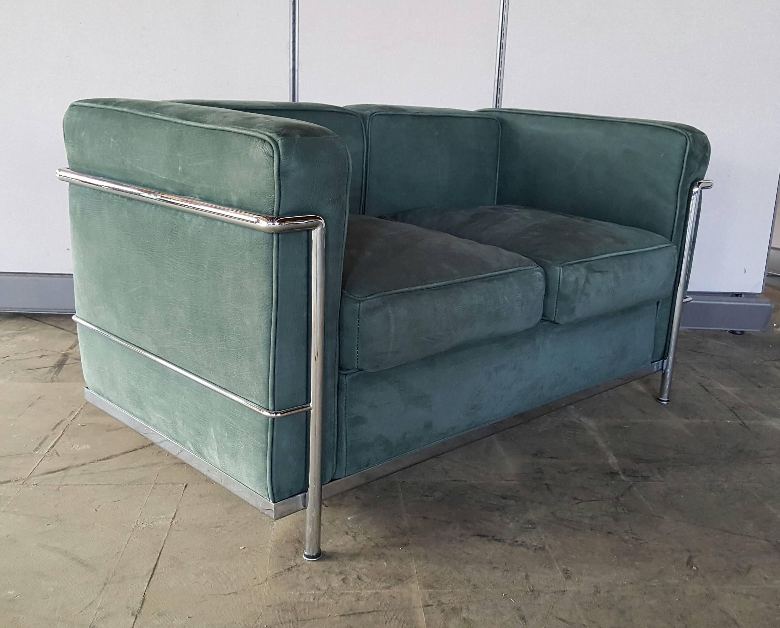 Beautiful LC3 two-seat sofa by Le Corbusier, made in Italy, circa 1980. This eye-catching sofa is upholstered in high quality emerald green suede and has a very recognizable chrome metal base, making it a very recognizable Le Corbusier piece that is