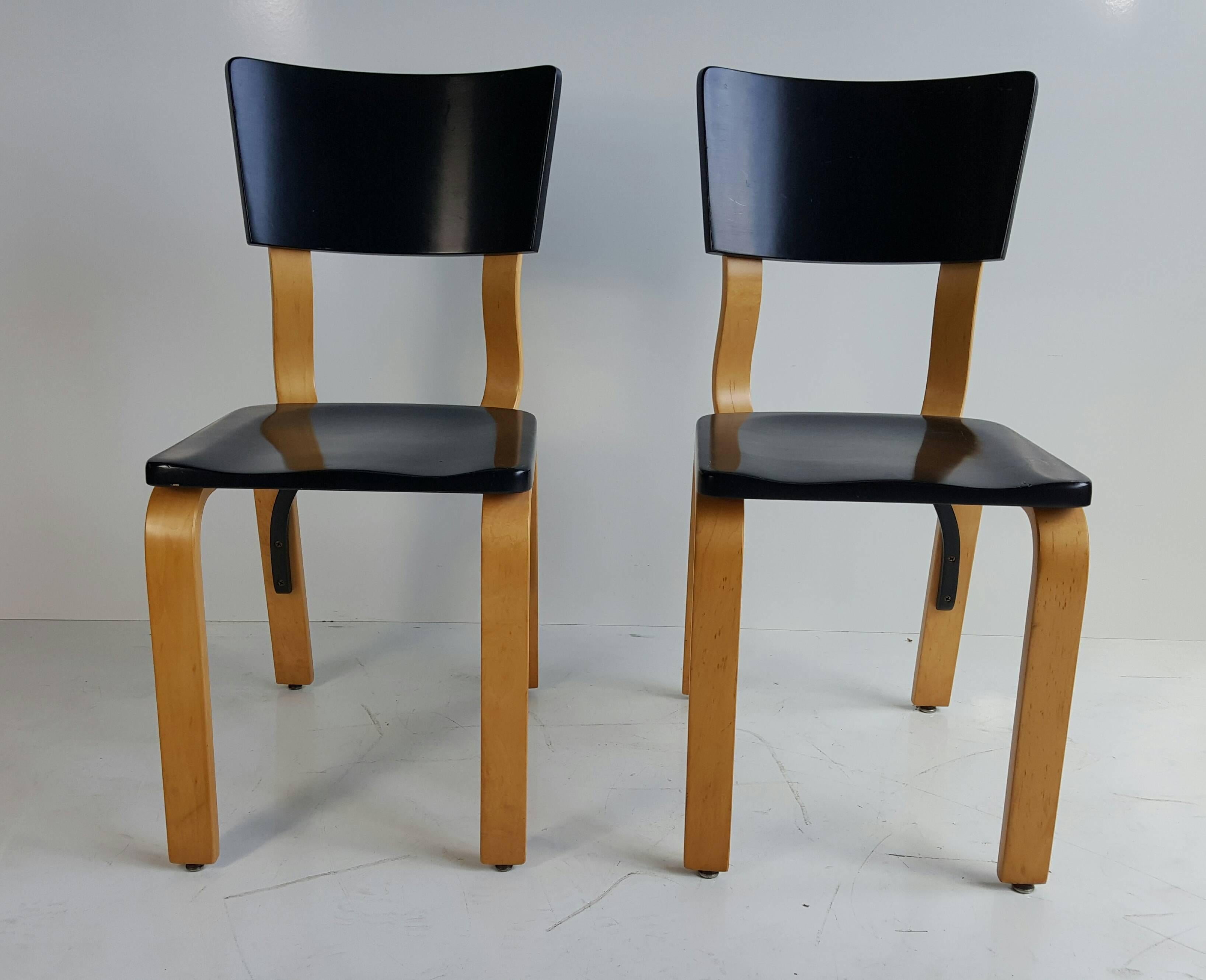 Classic modernist bentwood side chairs by Thonet. Black lacquer seat and back, bent plywood legs and back support.