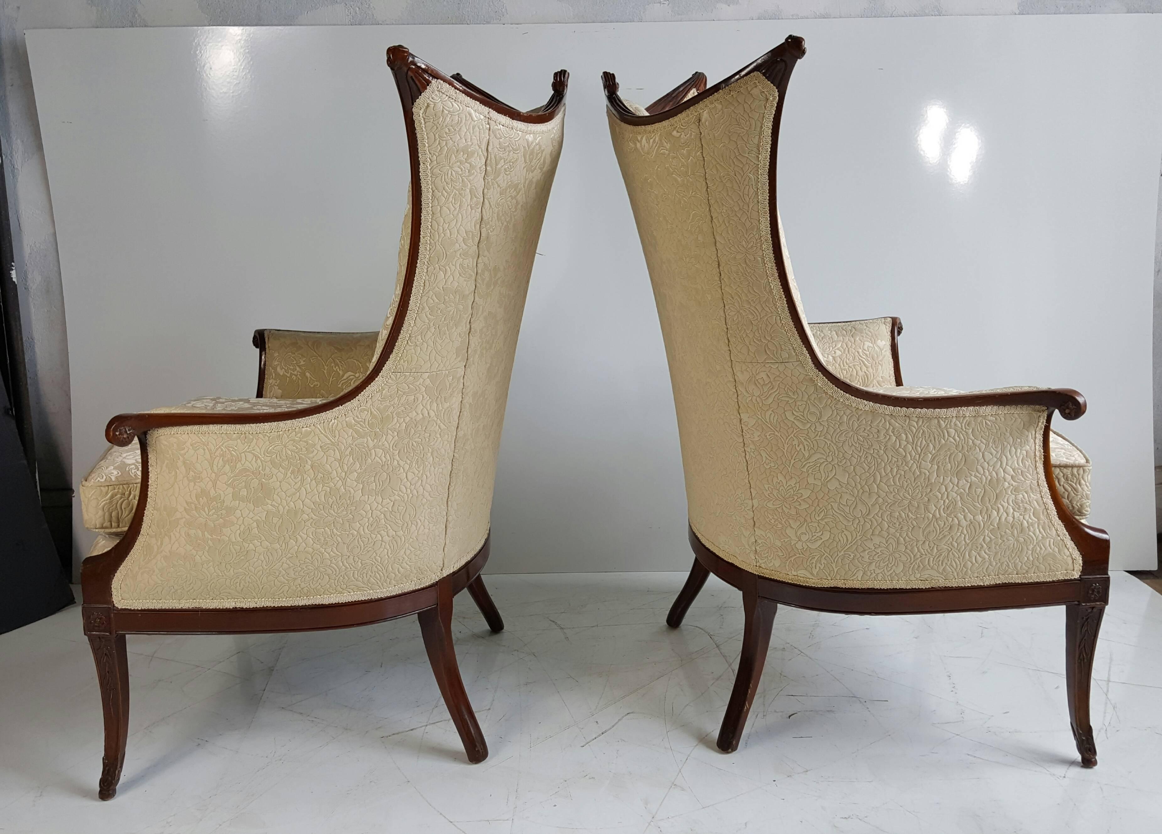 Pair of elegant Hollywood Regency bergères attributed to Grosfeld House. The mahogany frames are intricately carved with drapery and reeding and the elevated tablet is shaped and carved to echo the Directoire period. Wonderful design, superior
