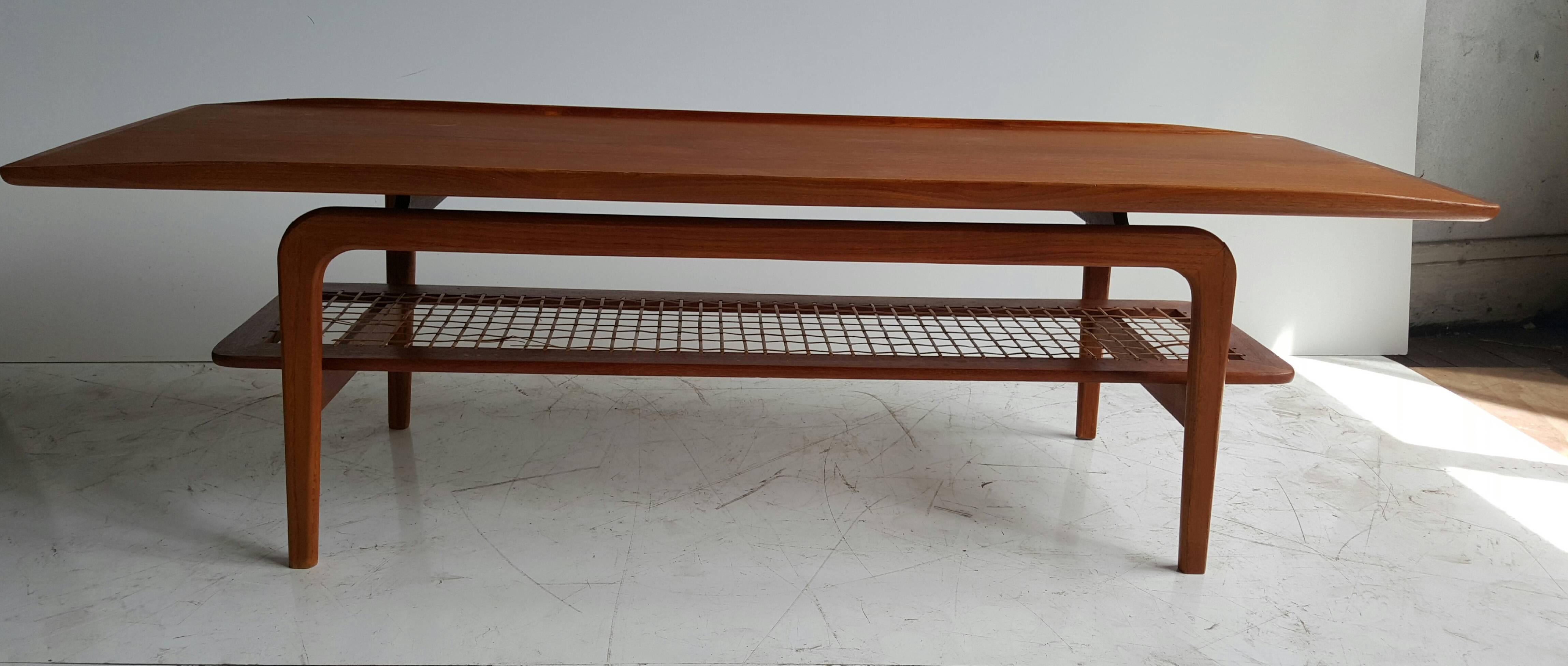 Beautiful vintage Danish coffee table with exquisite grains and colours. Subtle surfboard shape and lip sides to the top with a sturdy feel that contrasts nicely with lower tier shelf