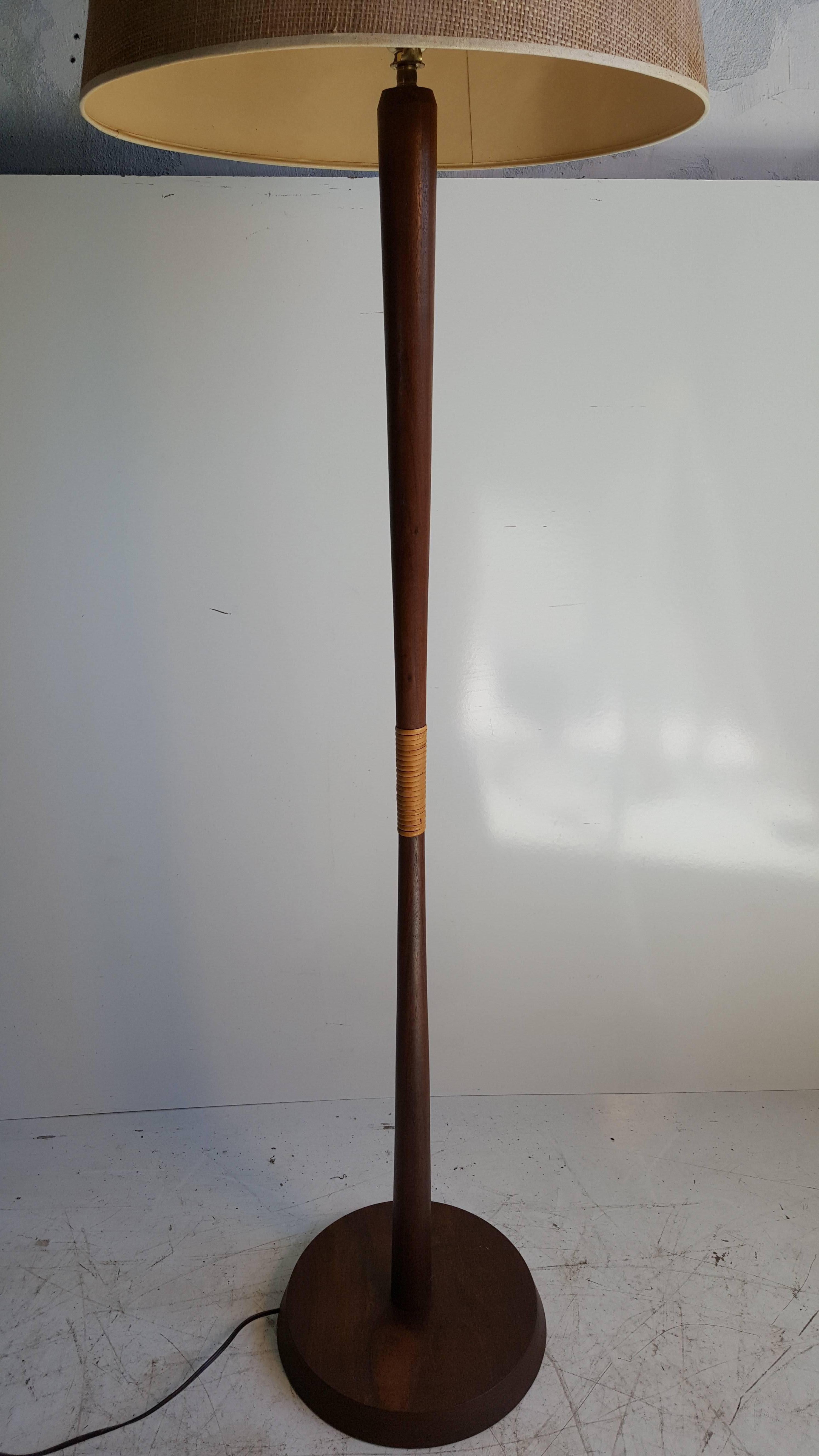 Classic turned walnut Danish modern taper floor lamp. Retains original shade in great condition, as well as simple reed wrap center detailing.