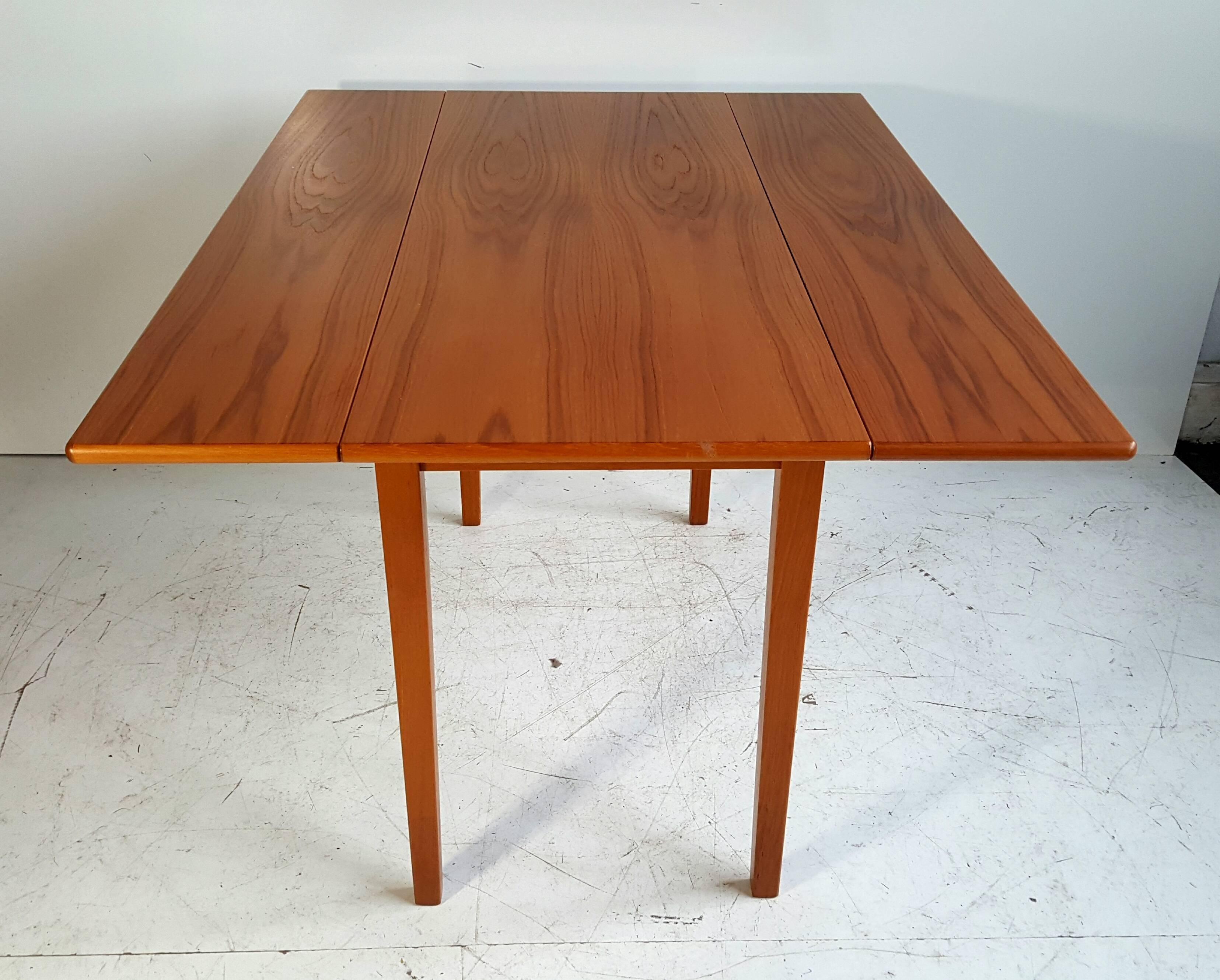 Classic Scandinavian design, sleek, simple, solid teak drop-leaf dining table, wonderful book matched graining, very versatile, when leaves are down table measures 47
