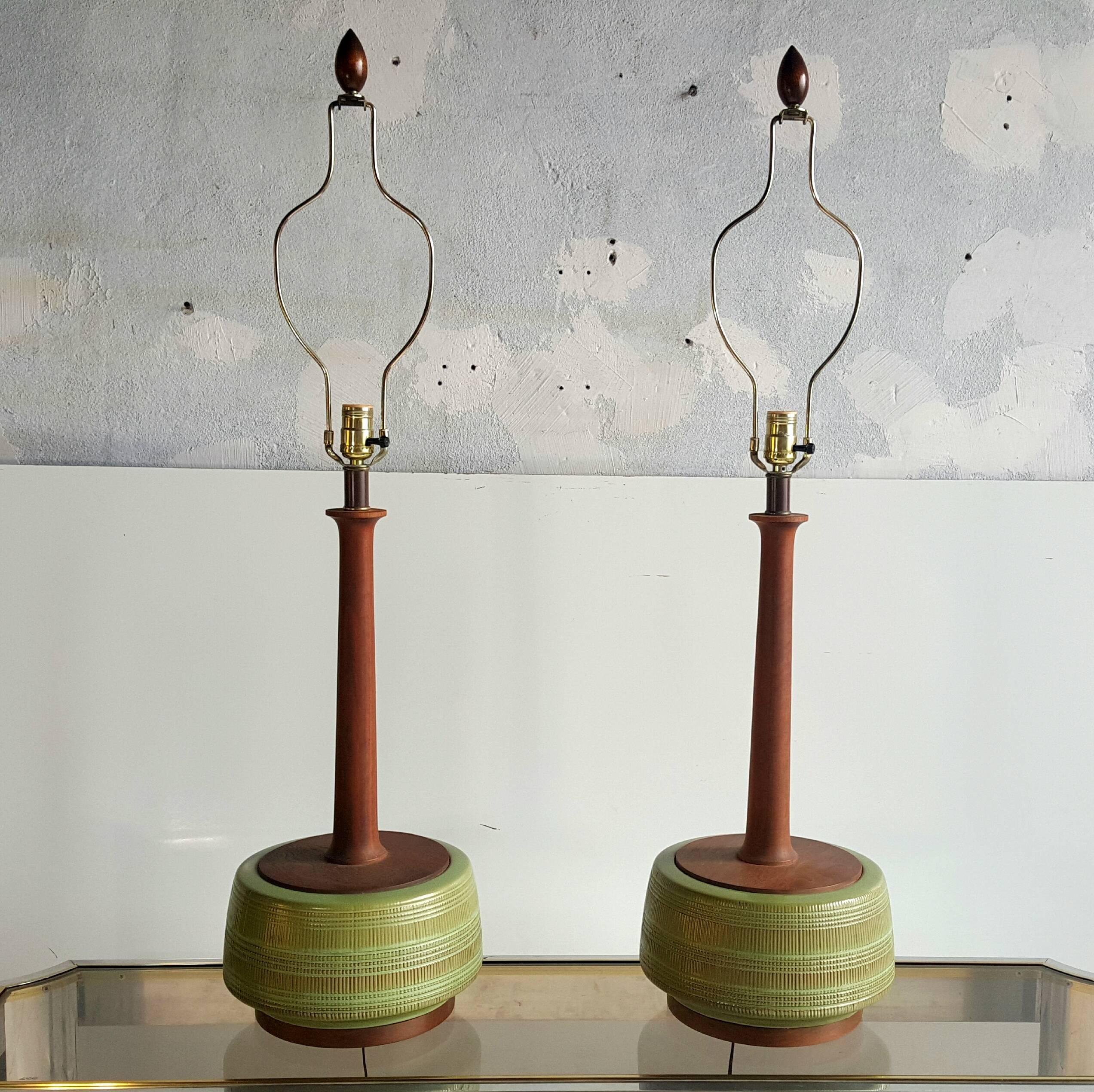 Classic Mid-Century Modern, stunning pair of tables made of decorative glazed pottery with teak wood standards, bases and finials, amazing color and finish, retain original lamp shades in wonderful condition.