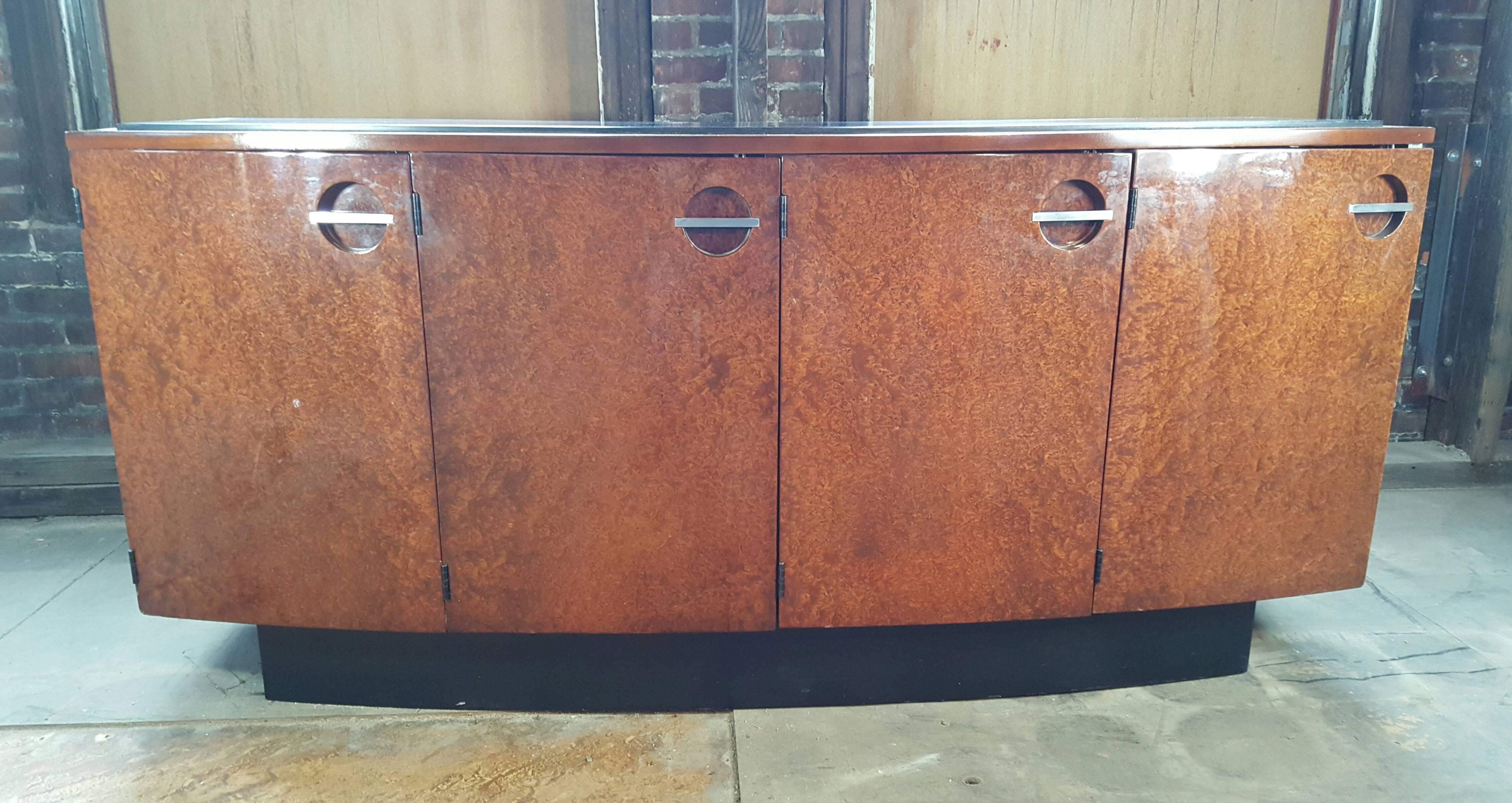 Classic Art Deco Burl Mahogany Sideboard. Designed in 1936 by Gilbert Rohde for Herman Miller. Stunning four-door curved cabinet featuring lacquered plinth as well as lacquered raised top. Right and left containing two shelves, center containing