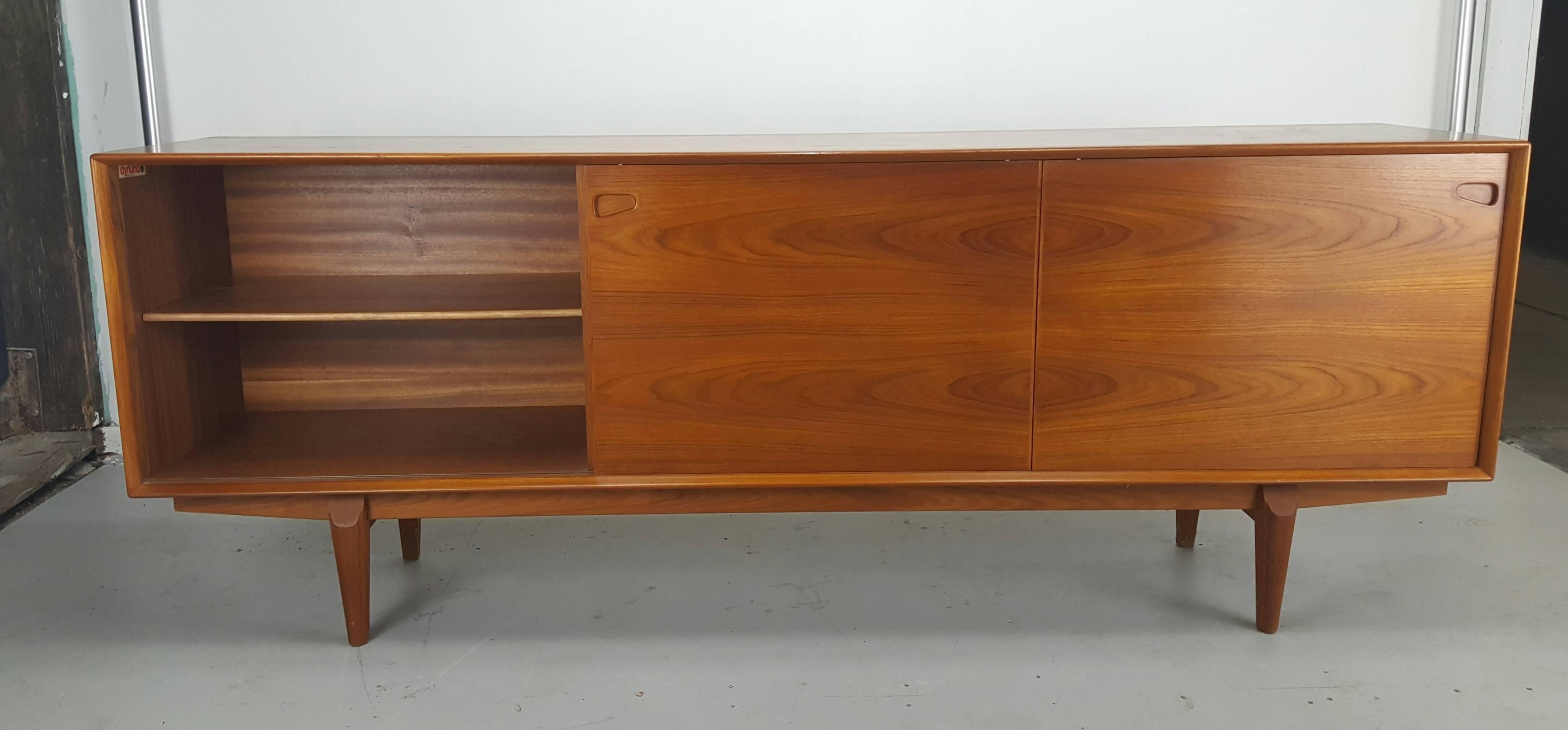 Denmark, 1960s.

This beautiful sideboard features a stunning bookmatched grain. With five sculptural drawers in the center and sliding doors on either side which reveal roomy shelving, Elegant and functional. Solidly constructed with tapered legs