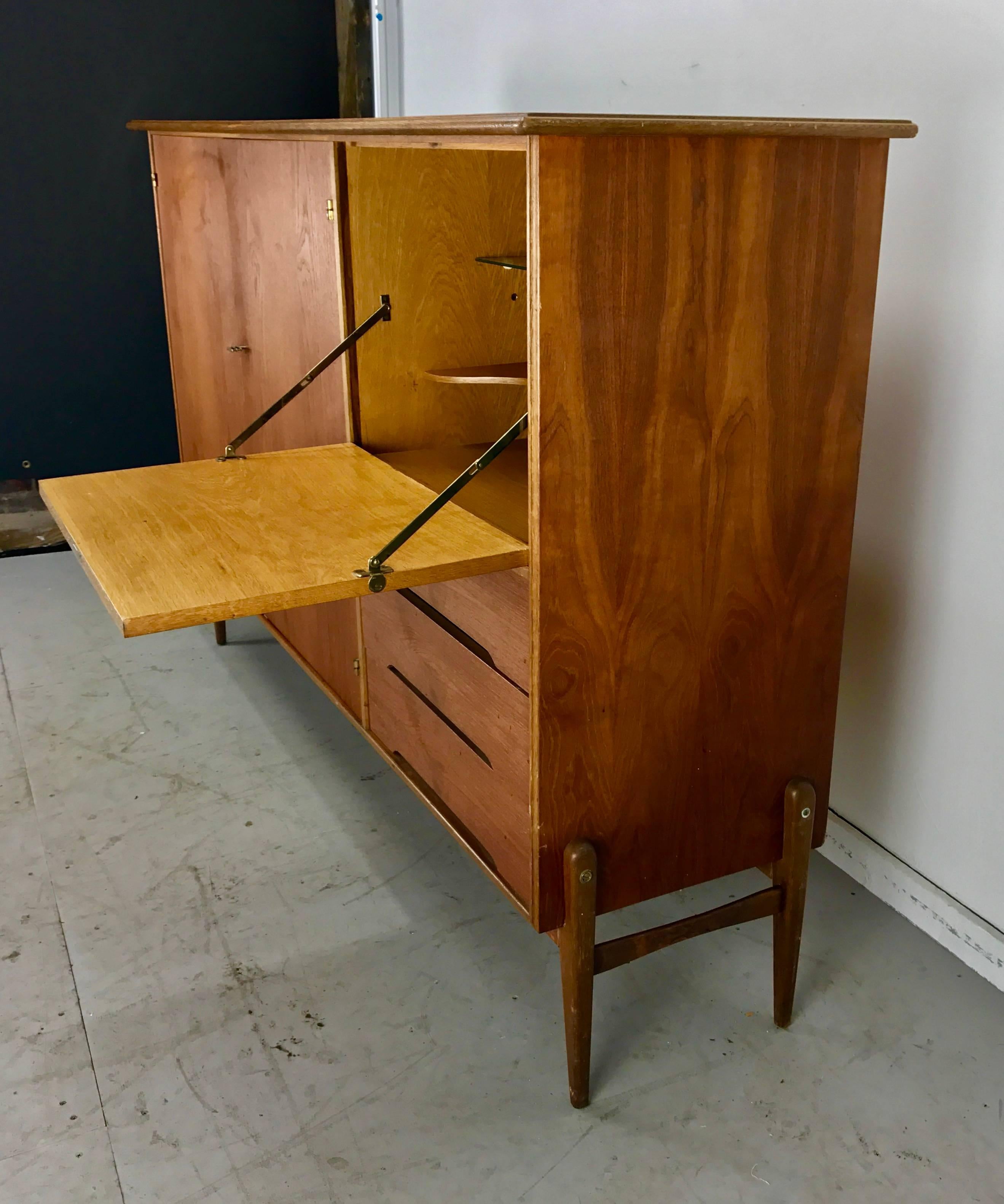 Stunning oak and teak cabinet/bar, early production made in Denmark, superior quality, dove-tail joinery, locking, featuring generous two-door cabinet/three shelves, drop down door, glass and wood shelf with three drawers below, super sexy,