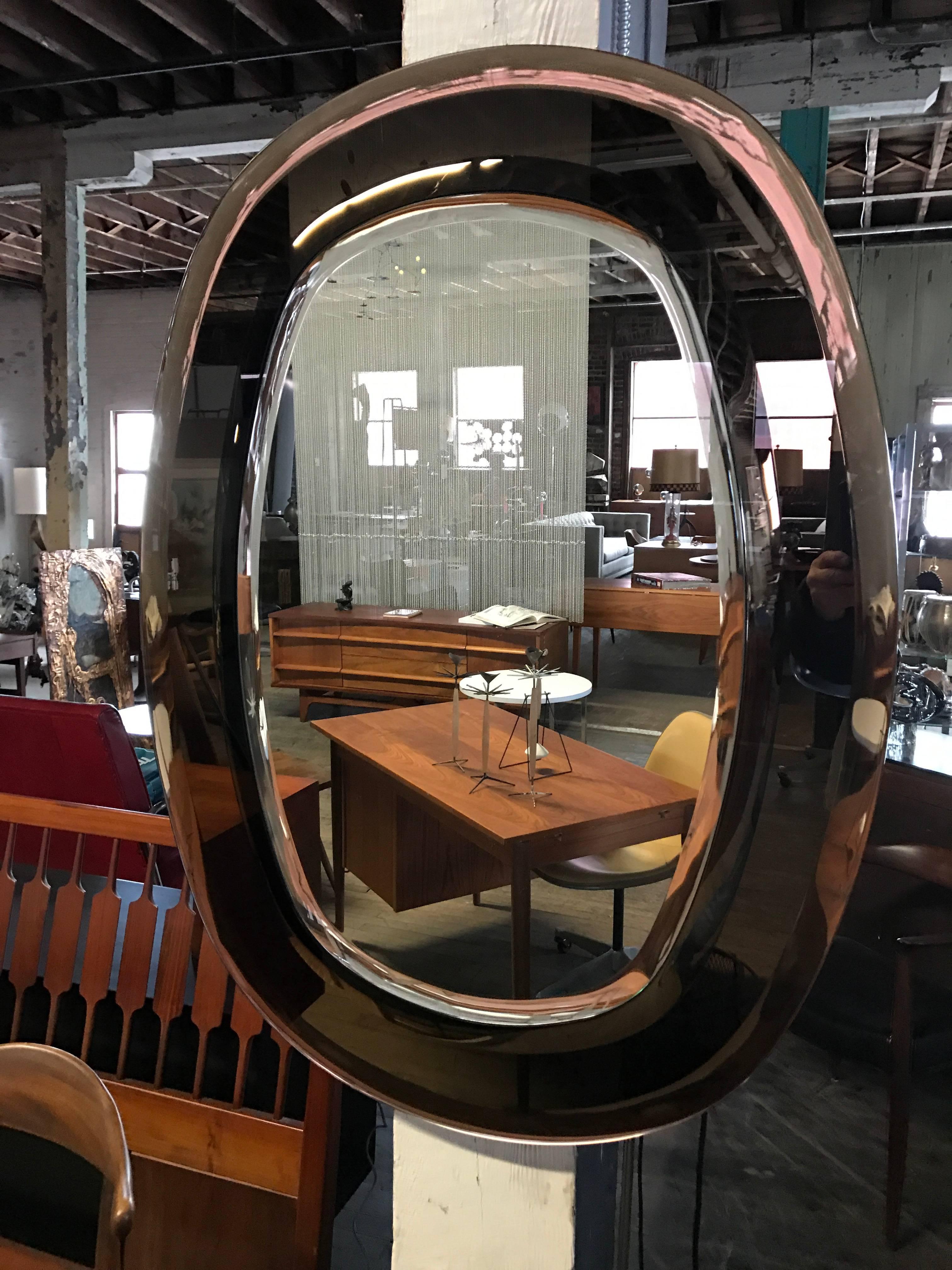 Elegant Italian wall mirror with smoke and smokey brown copper mirror frame, The oval shaped central glass mirror is beveled and is floated over a larger smoke colored mirror that is also beveled. A true Classic Mid-Century Italian mirror.
 