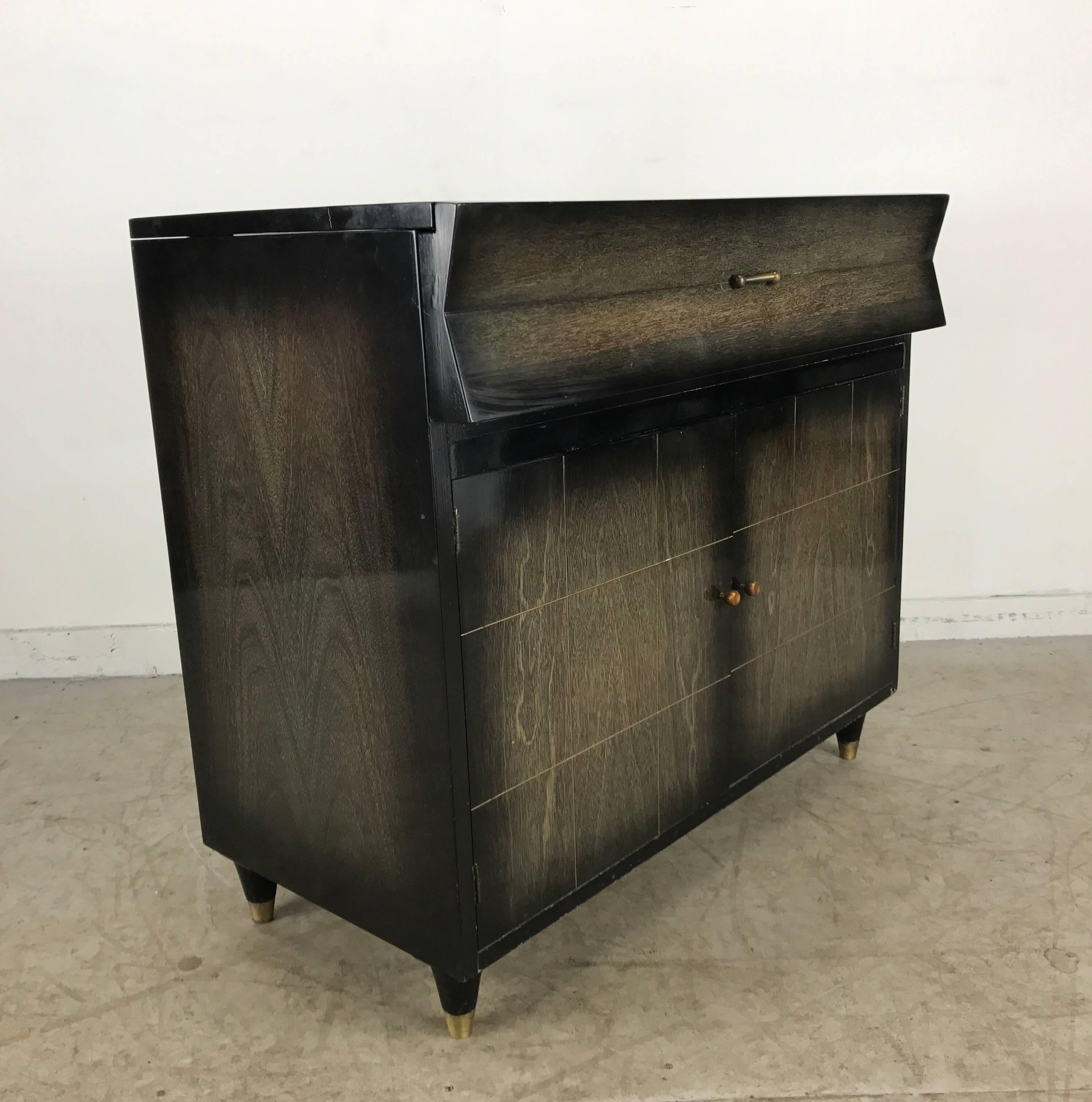 Classic modernist dry bar. Original limed oak finish. Top opens revealing full service bar. 18 glasses, front panel drops for ample serving surface.Two doors (bottom) roomy storage for liquor, also retains handy drawer. Handsome mid century design.