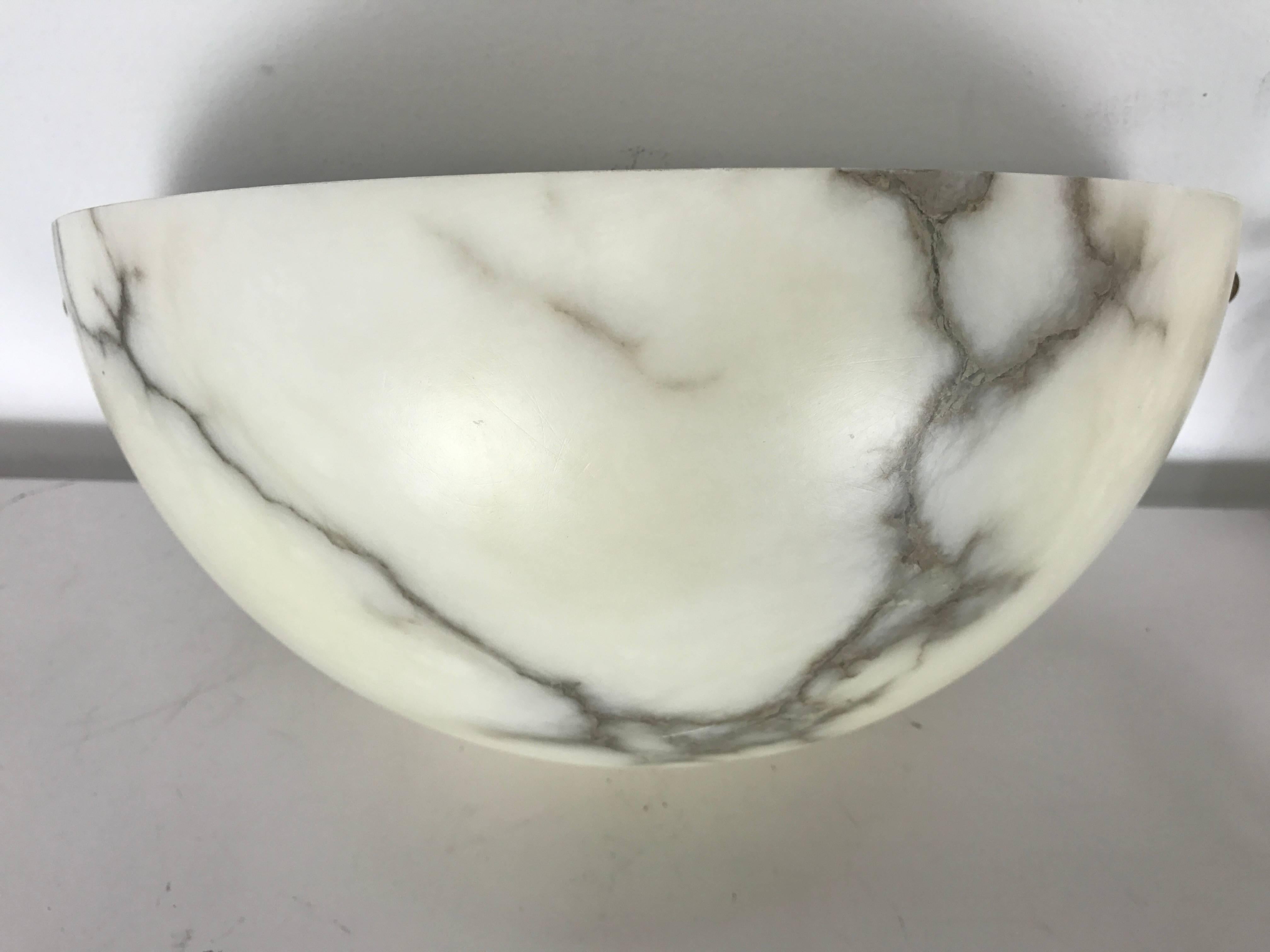 Pair of alabaster clean lined quarter sphere wall sconces by Lightolier. Classic Art Deco Styling,, Fixtures held flush to the wall on hidden white painted back plates held in place with small brass round finials.