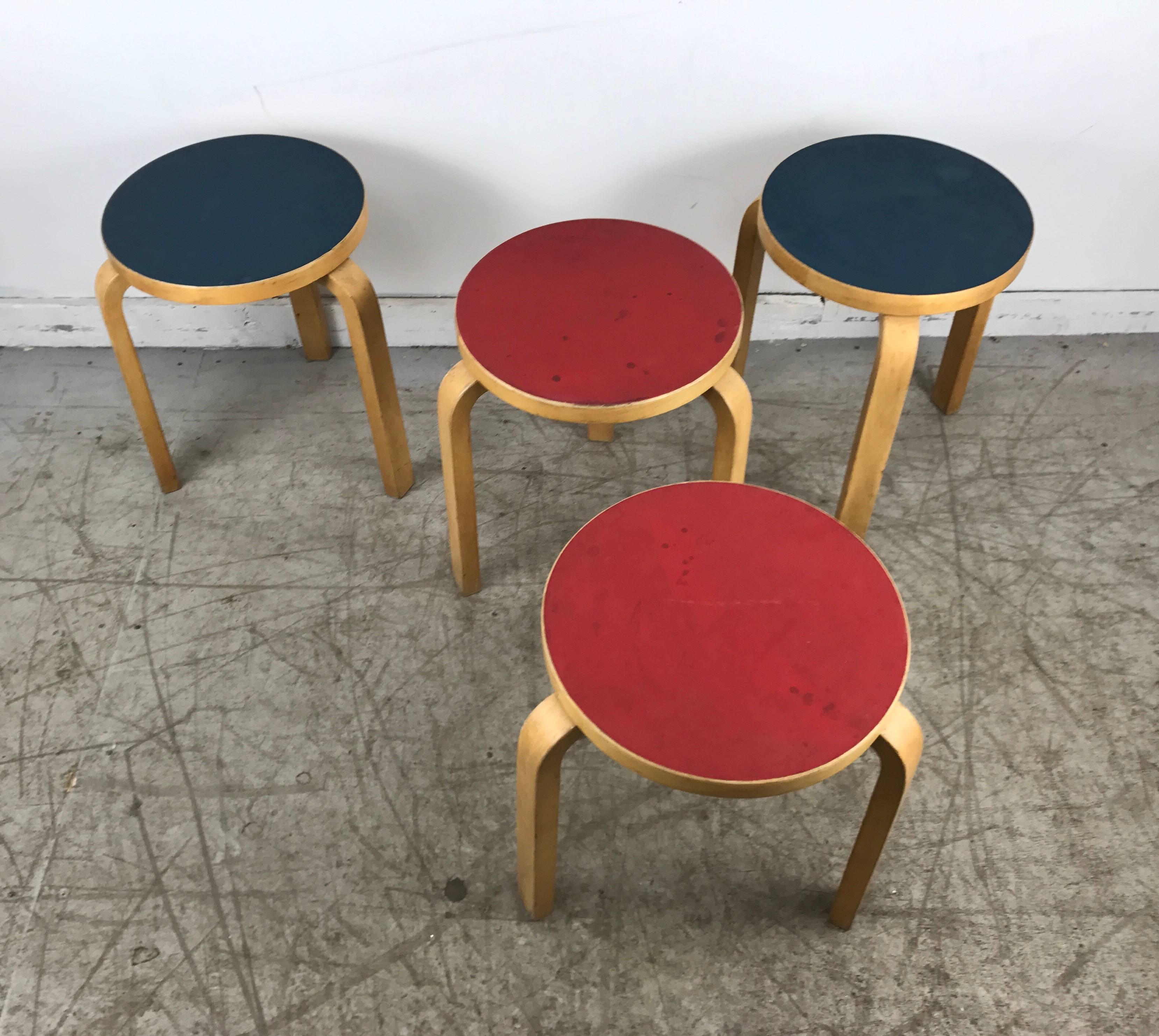 Four stacking stools, model 60 by Alvar Aalto, original beechwood, with original thin laminate / linoleum tops, two blue, two red.