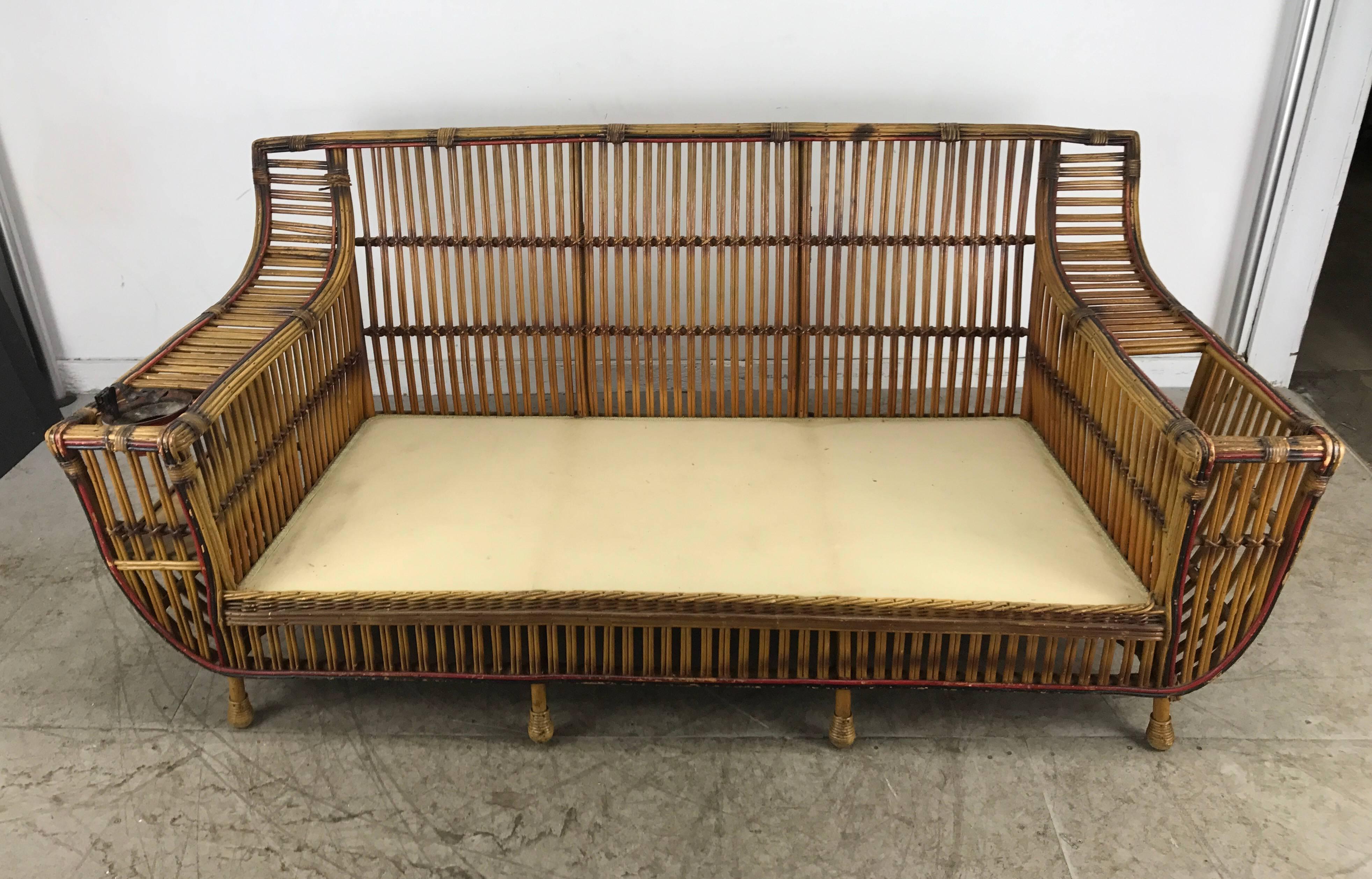 Stunning Art Deco split reed / stick wicker three seat sofa by Niagara Reedcraft Inc. Niagara Falls NY, Retains original natural finish accented by red and black detailing, also retains original ash receptical. Amazing styling featuring bookcase