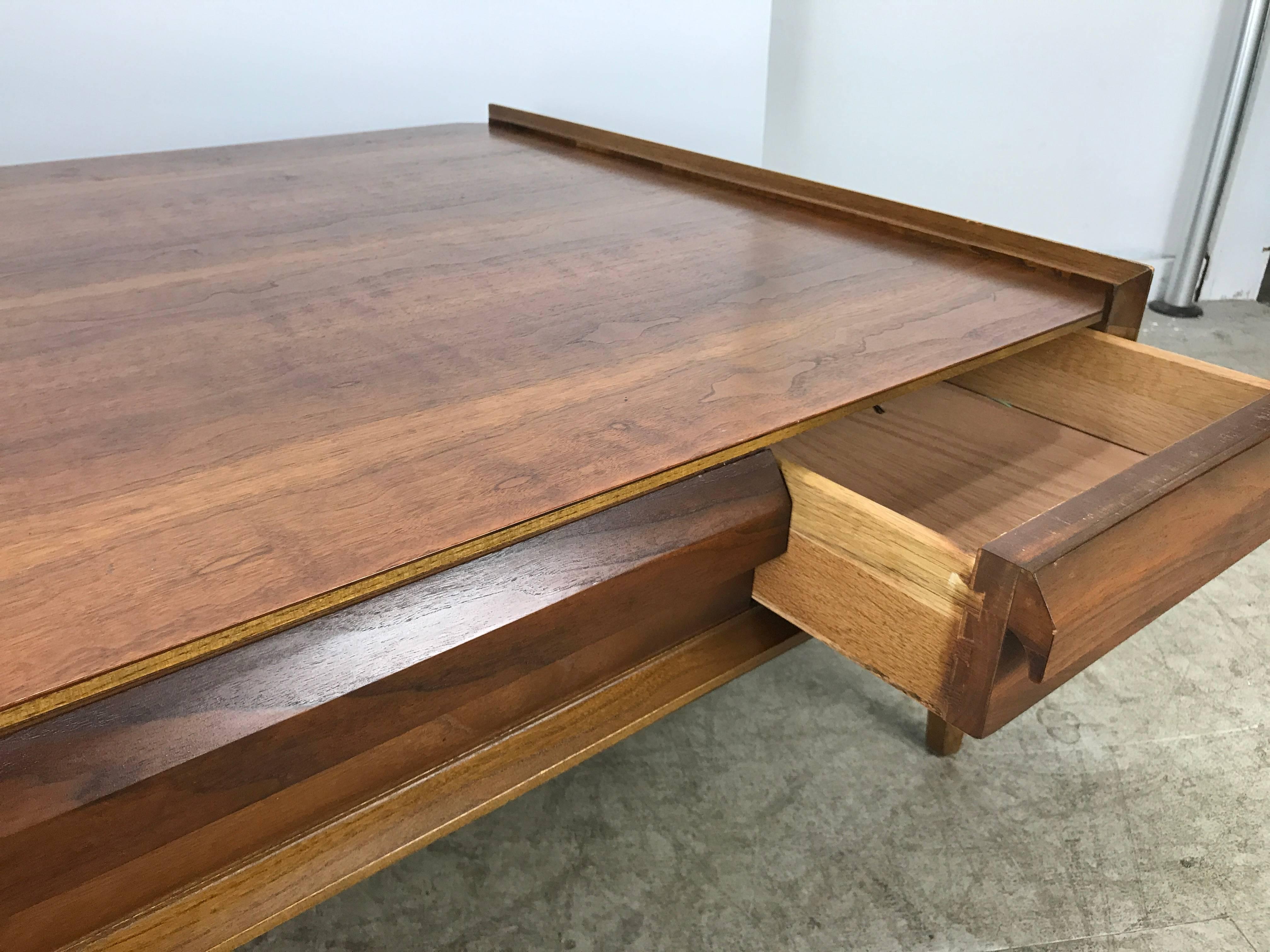 Modernist figured walnut cocktail table by Andre Bus for Lane. Classic modernist design, wonderful figured walnut, superior quality and construction, featuring 12 inch x 33 inch single drawer that opens from either side. Stunning! Hand delivery