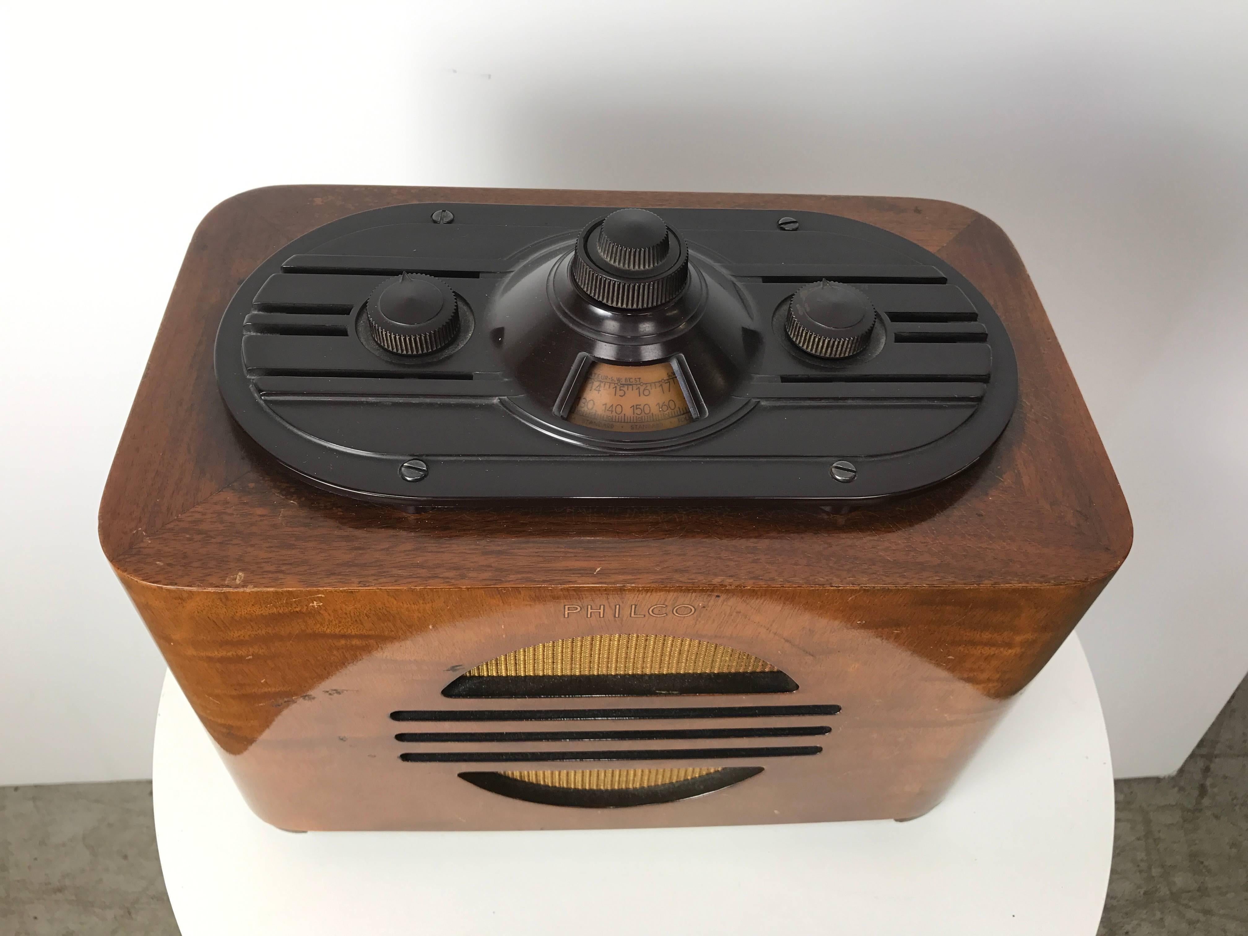 Walnut and Bakelite streamline tube radio manufactured by Philco designed by Norman Bel Geddes, Amazing Art Deco design, excellent original condition, Unusual Bakelite tuner, volume configuration, speakers on each side, tested and works perfectly.