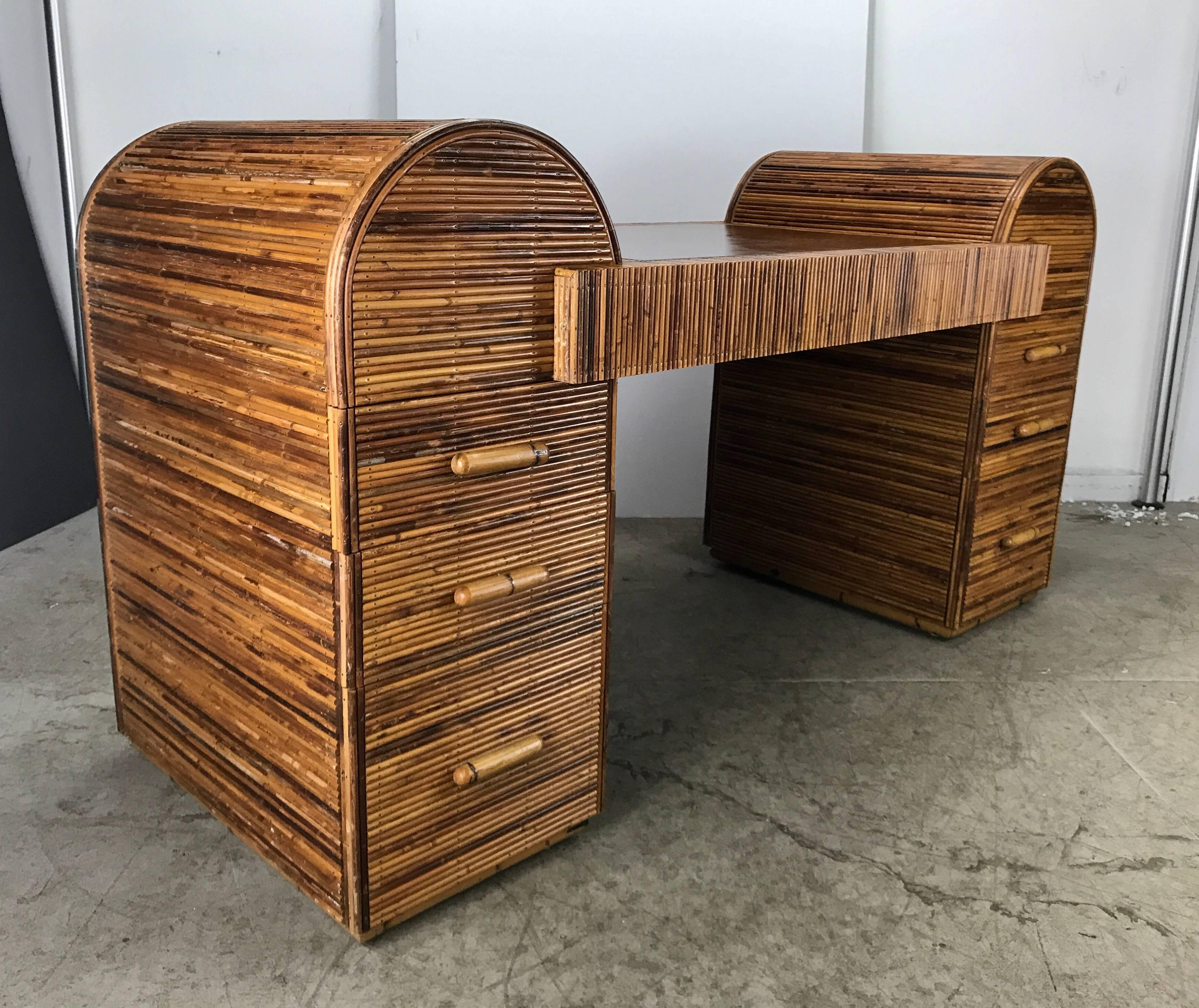 Unusual Art Deco split reed / stick wicker desk with compelling architectural lines and dramatic presence.

Two end pieces with three drawers each, rise above center work area with arched perfection and amplify the Art Deco design.

Stunning