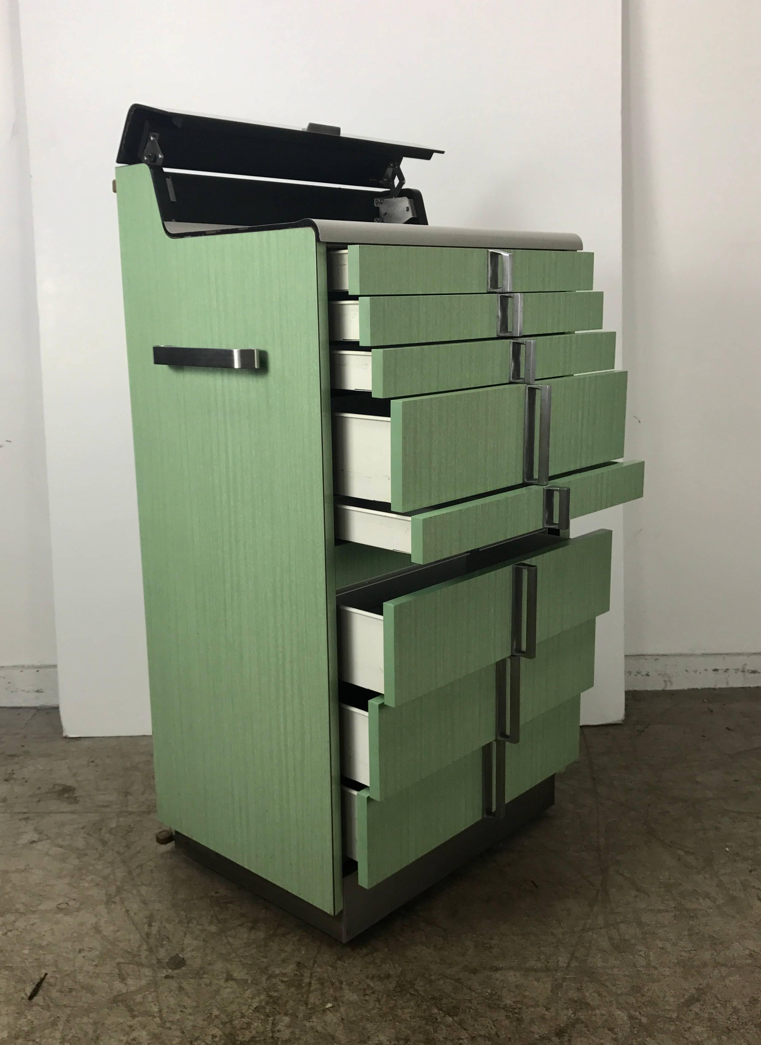 Art Deco multi drawer Dental Cabinet. Industrial metal manufactured by Hamilton,, Wonderful design, stainless steel accents., Retains original milk glass divided trays flip-top for additional storage. On wheels with fabulous towel bar handles