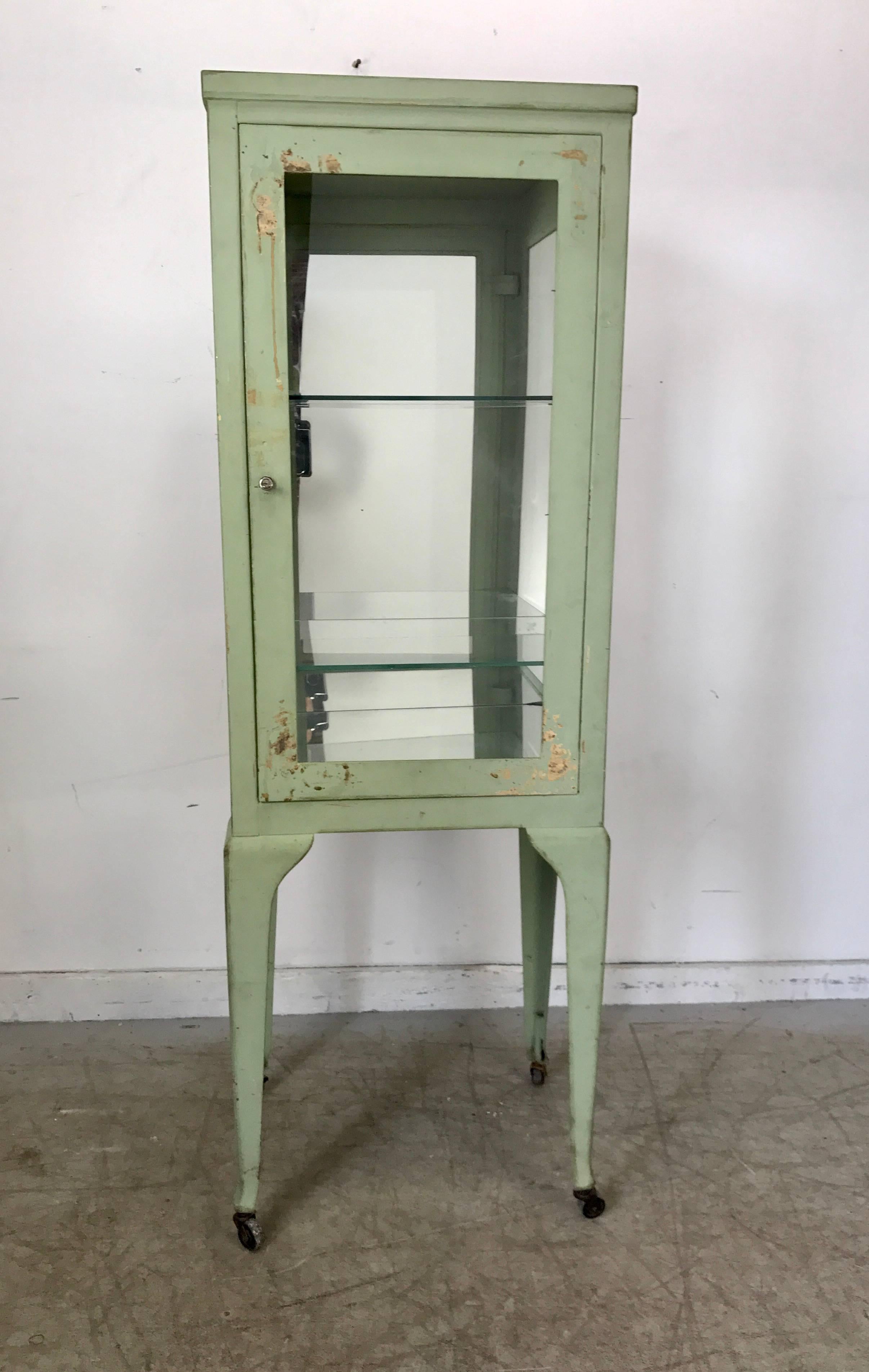 Classic 1920s metal and glass specimen cabinet, medical, Industrial. Wonderful patina color, surface and proportion, retains original locking mechanism and key, hand delivery avail to New York city or anywhere en route from Buffalo New York.