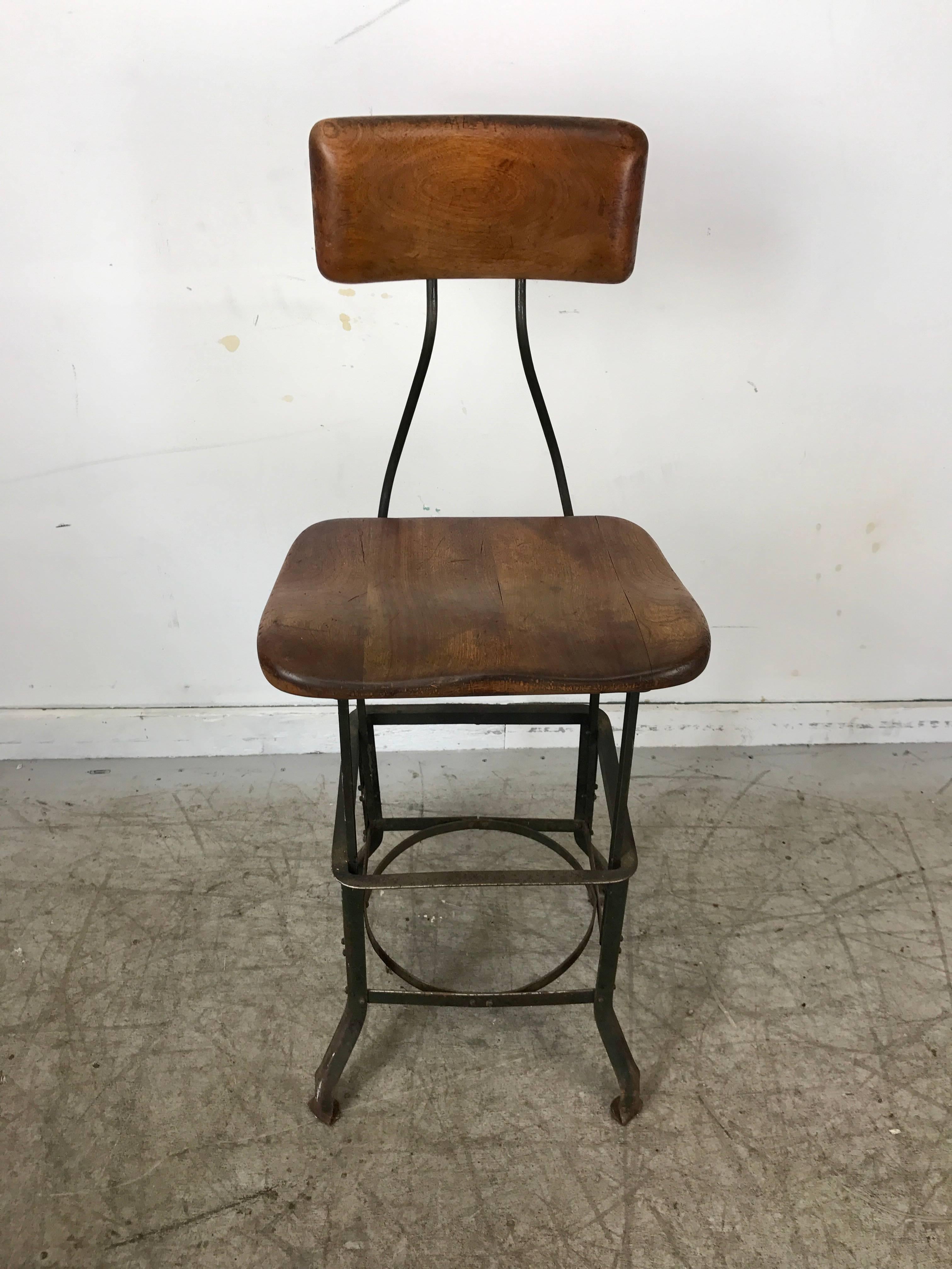 Early adjustable Industrial machinist stool, manufactured by Toledo,, Wonderful original patina color and surface. Solid carved wood top and back.