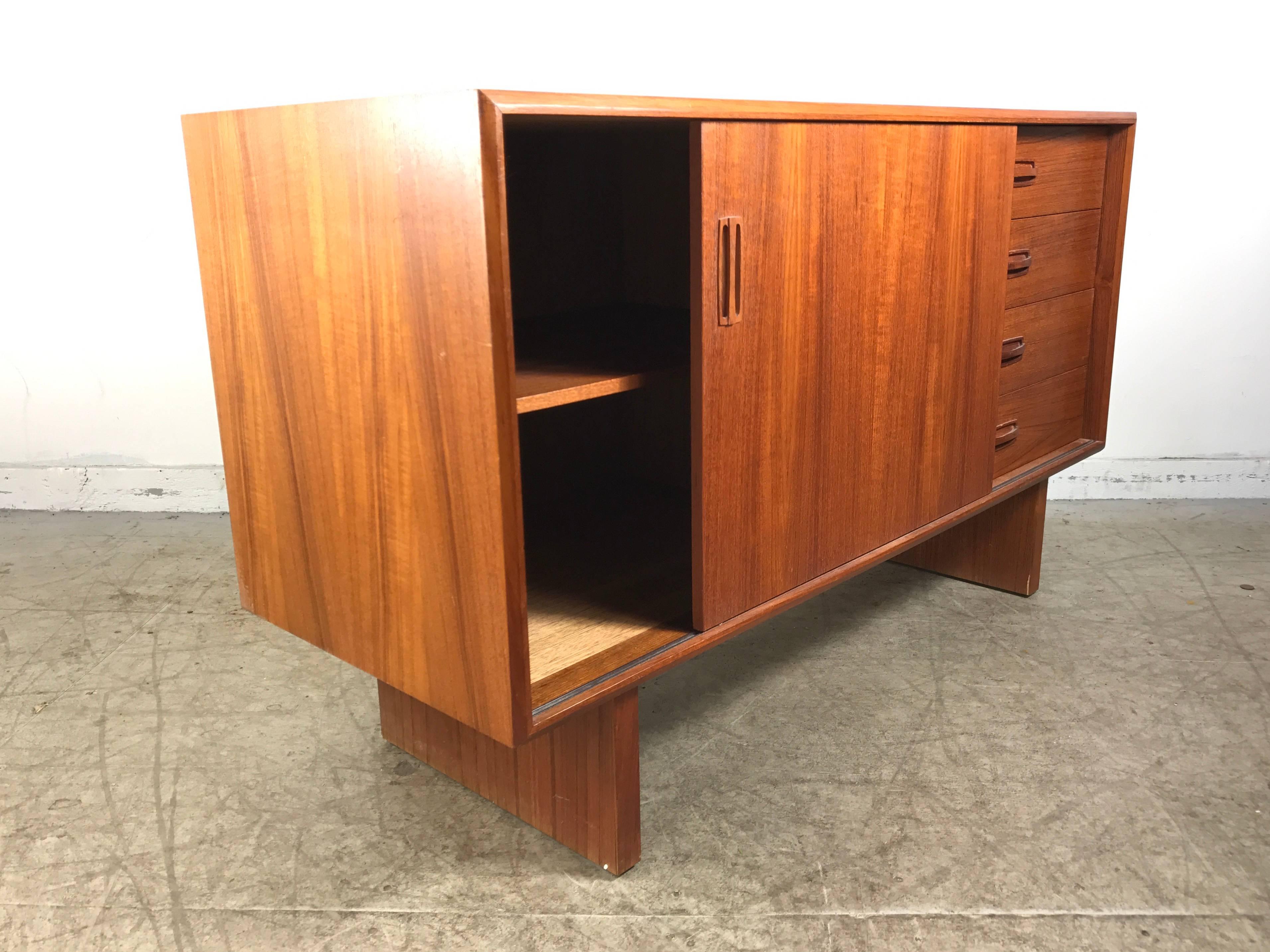 Classic Danish modernist 4' teak credenza, server in the manner of Arne Vodder. Wonderful, warm teak wood construction, cabinet features four drawers to right side, sliding door with one shelf, sleek, simple design with stunning drawer and door