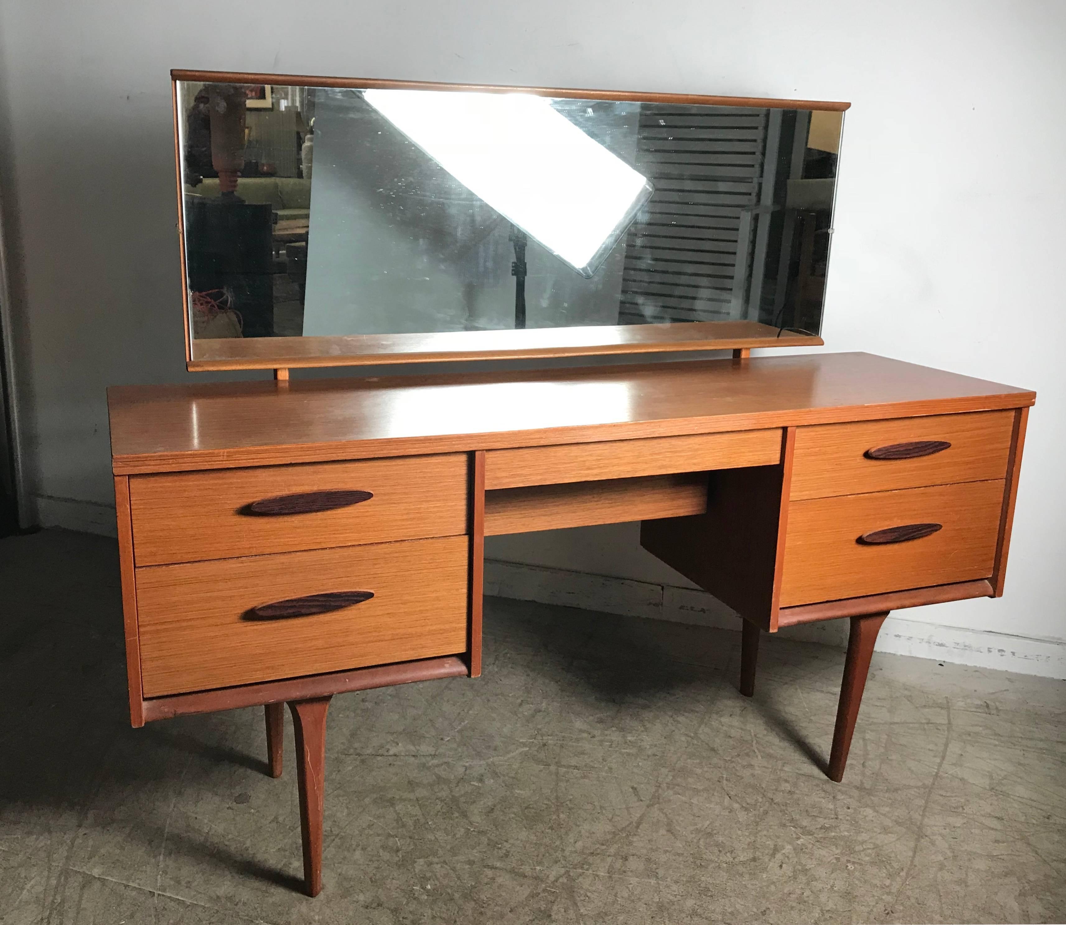 Unusual modernist vanity/desk made in Denmark, adjustable pivoting rectangular mirror. Four-drawer left and right, center drawer with secondary deep storage, rosewood drawer pulls.
  