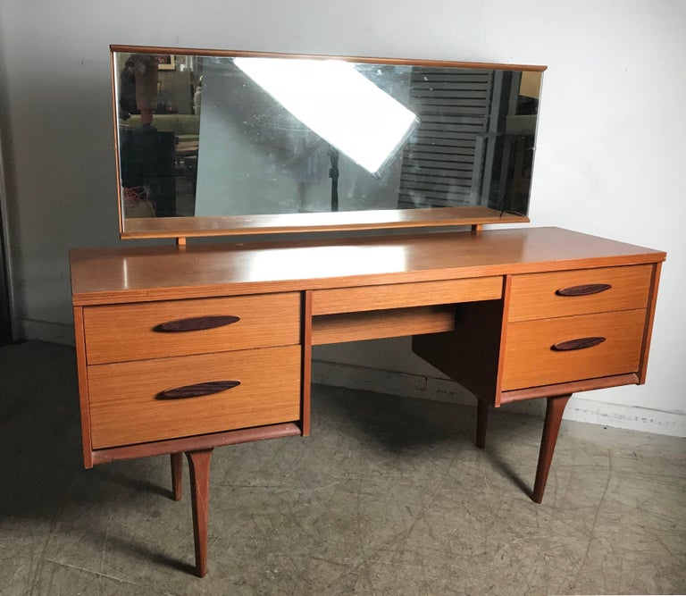 Unusual modernist vanity/desk made in Denmark, adjustable pivoting rectangular mirror. Four-drawer left and right, center drawer with secondary deep storage, rosewood drawer pulls.
  