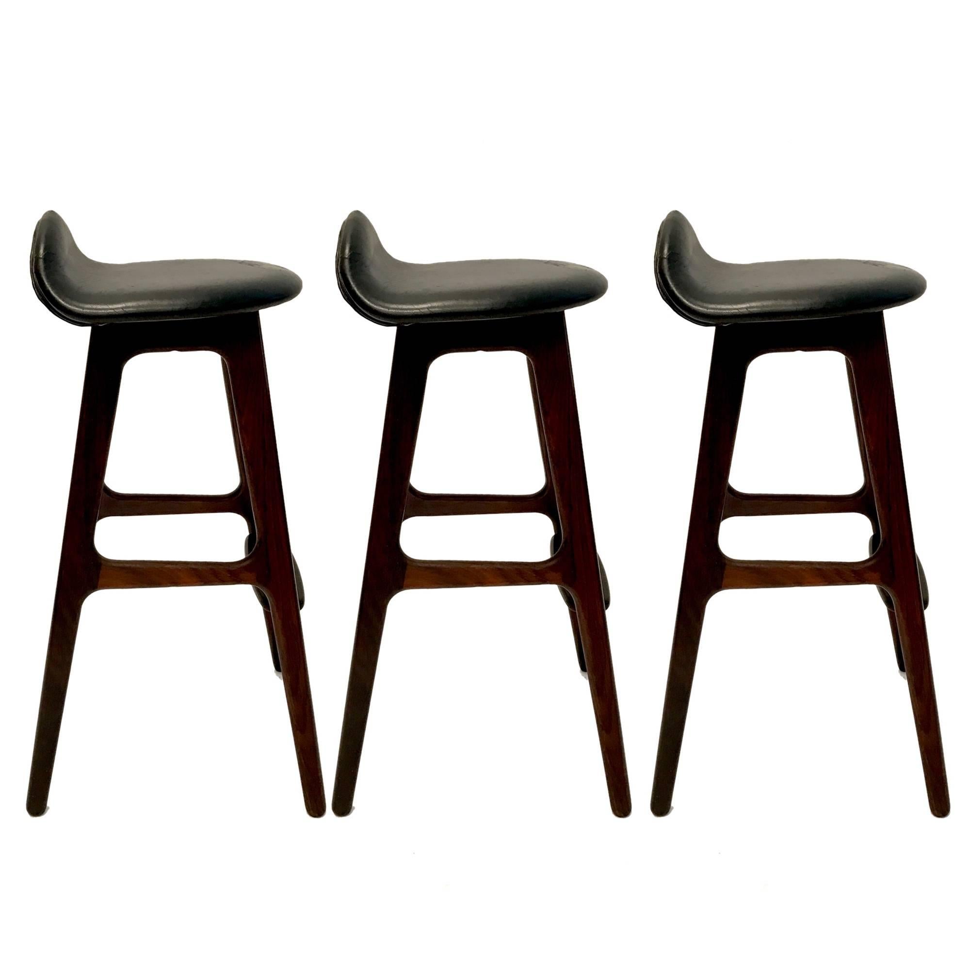 Set of three gorgeous barstools. Rosewood frames with original black leather bar seats. These stools were in the fictional apartment of 