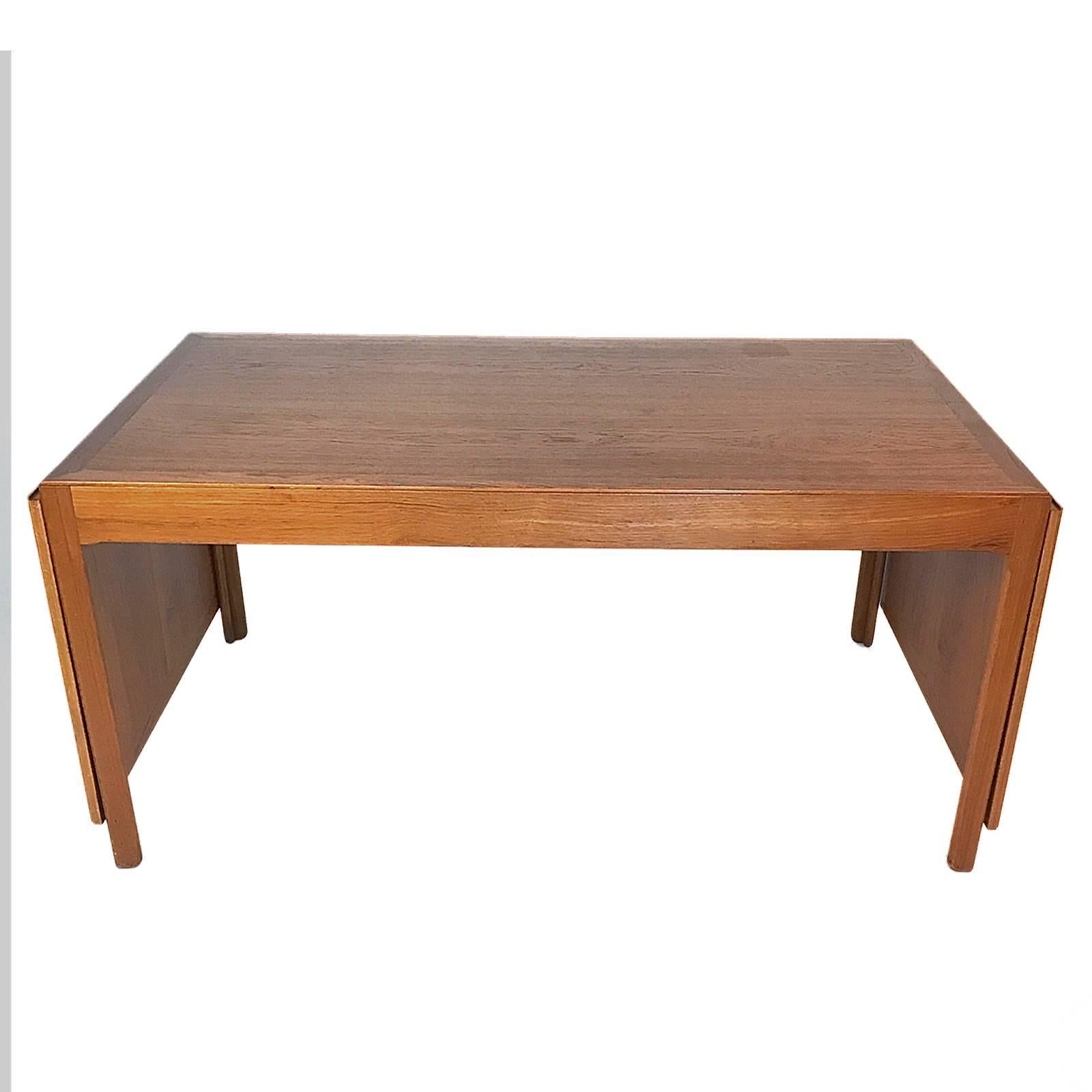 A teak dining table with profiled legs and edges. Top has detachable drop down leafs with brass fittings. This example was made by cabinetmaker Erhard Rasmussen in the1960s.The top measures 58 5/8 when the leaves are down or removed. Each leaf