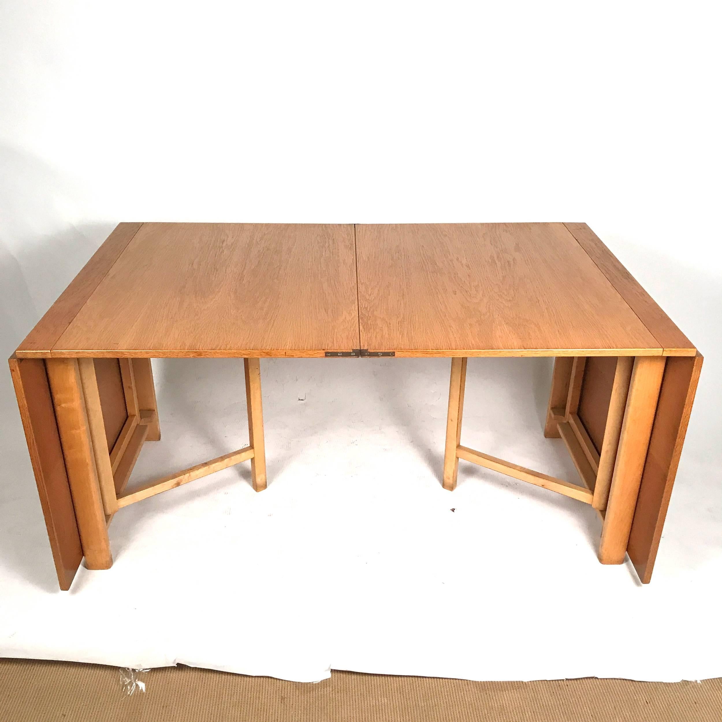 This is an early example from the late 1930s-1940s in oak with beech legs signed on retaining bar. A very versatile table that can seat up to ten or fold to a compact size, perfect for apartments or large dining rooms. The table measures 9.5 inches