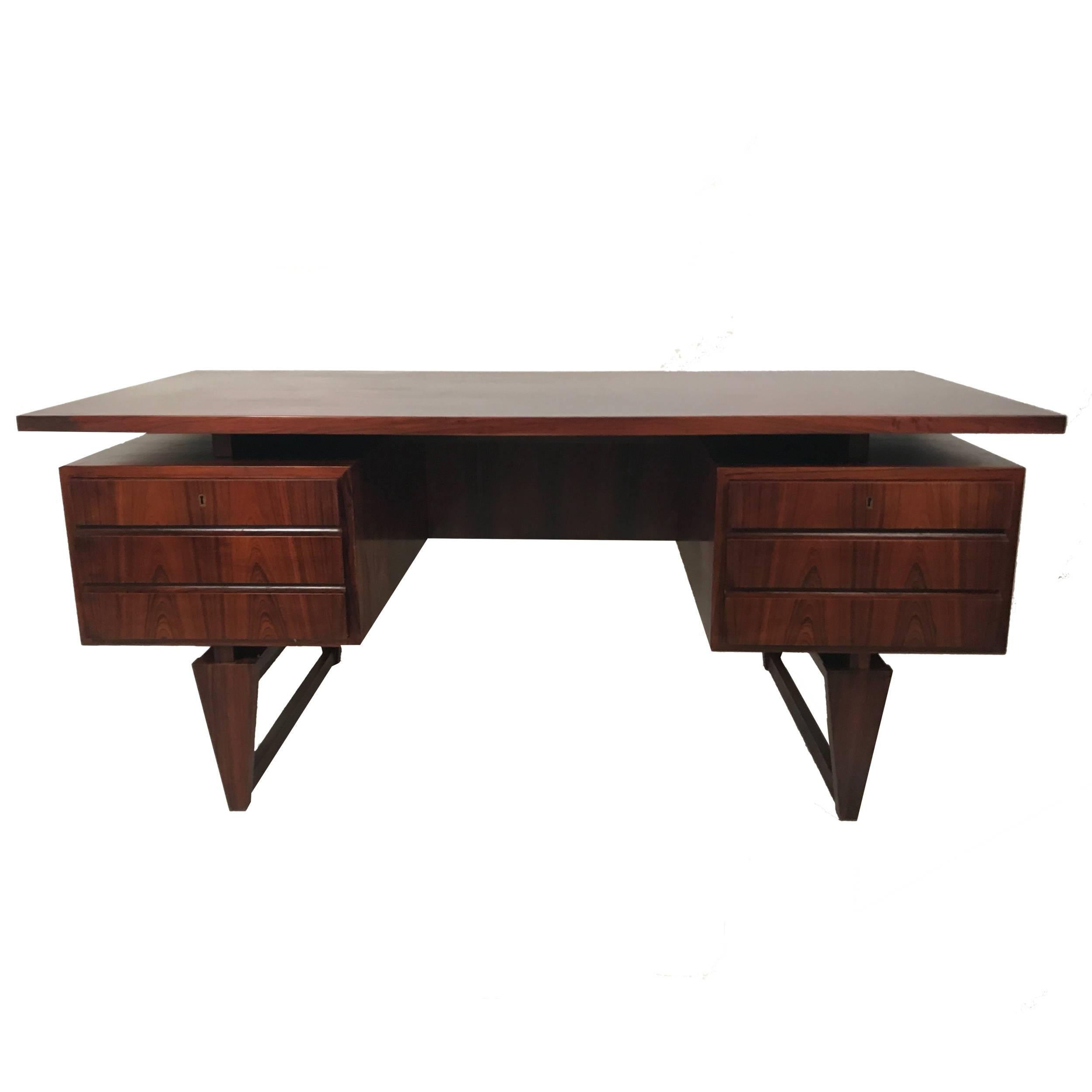 A very sleek exotic desk in rosewood by Illum Wikkelsø with six drawers and a finished back. Very nice original finish with a little shading on top from blotter. Retains original brass key to lock drawers. Absolutely stunning piece!