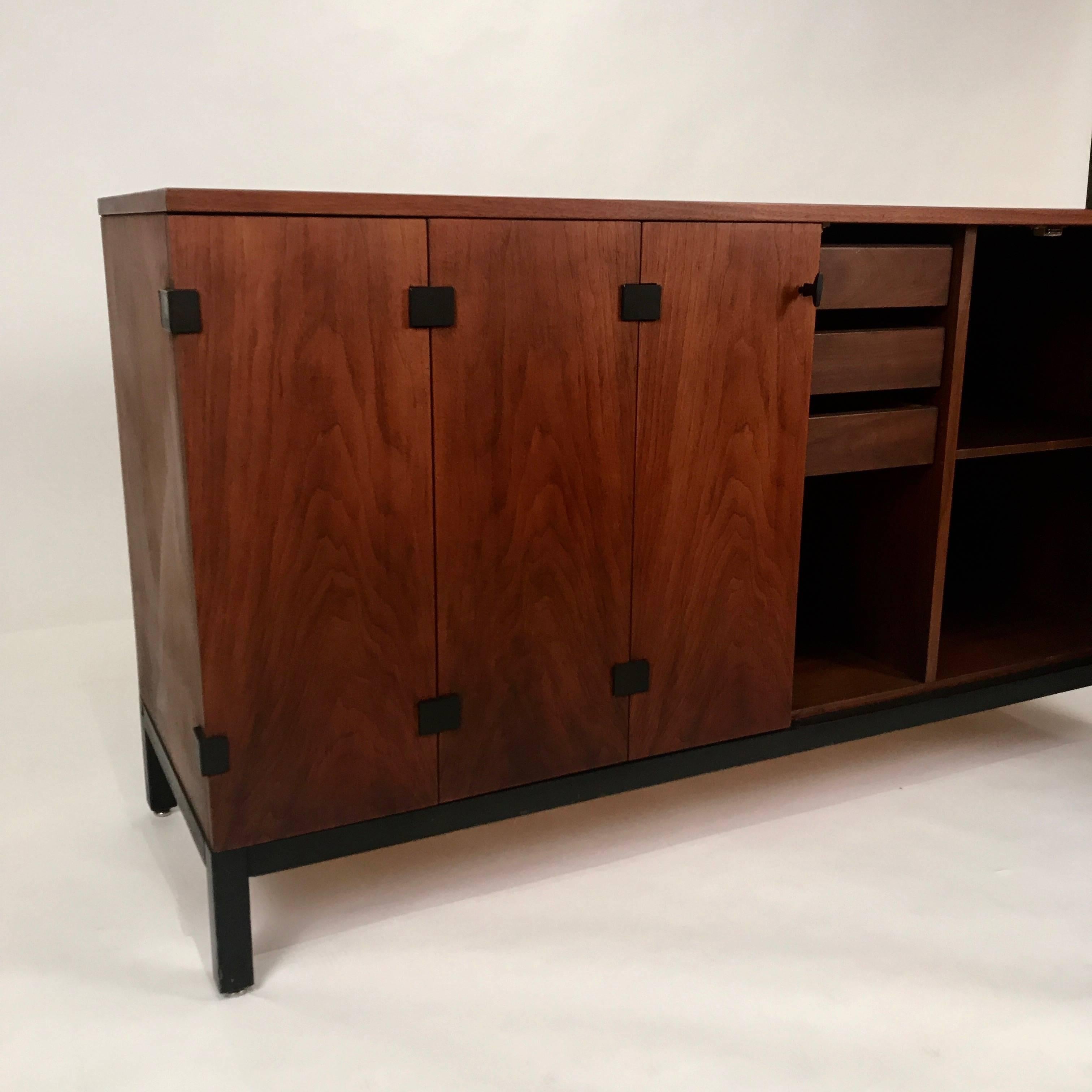 Really great walnut sideboard. Still looks like new. Black iron hardware on stunning tri-fold doors. Interior houses much shelf space and three drawers including a silverware storage drawer.