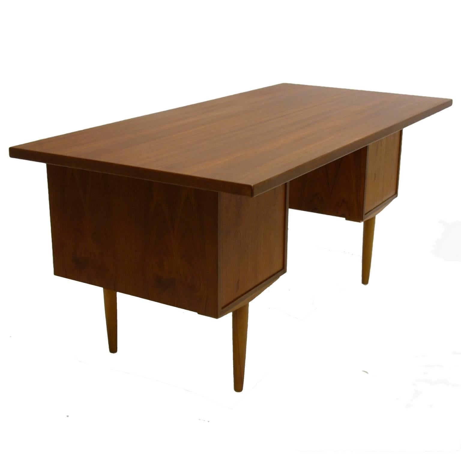Lovely and functional teak desk. Large desktop area along with three drawers on one side and one large file drawer on the other side.