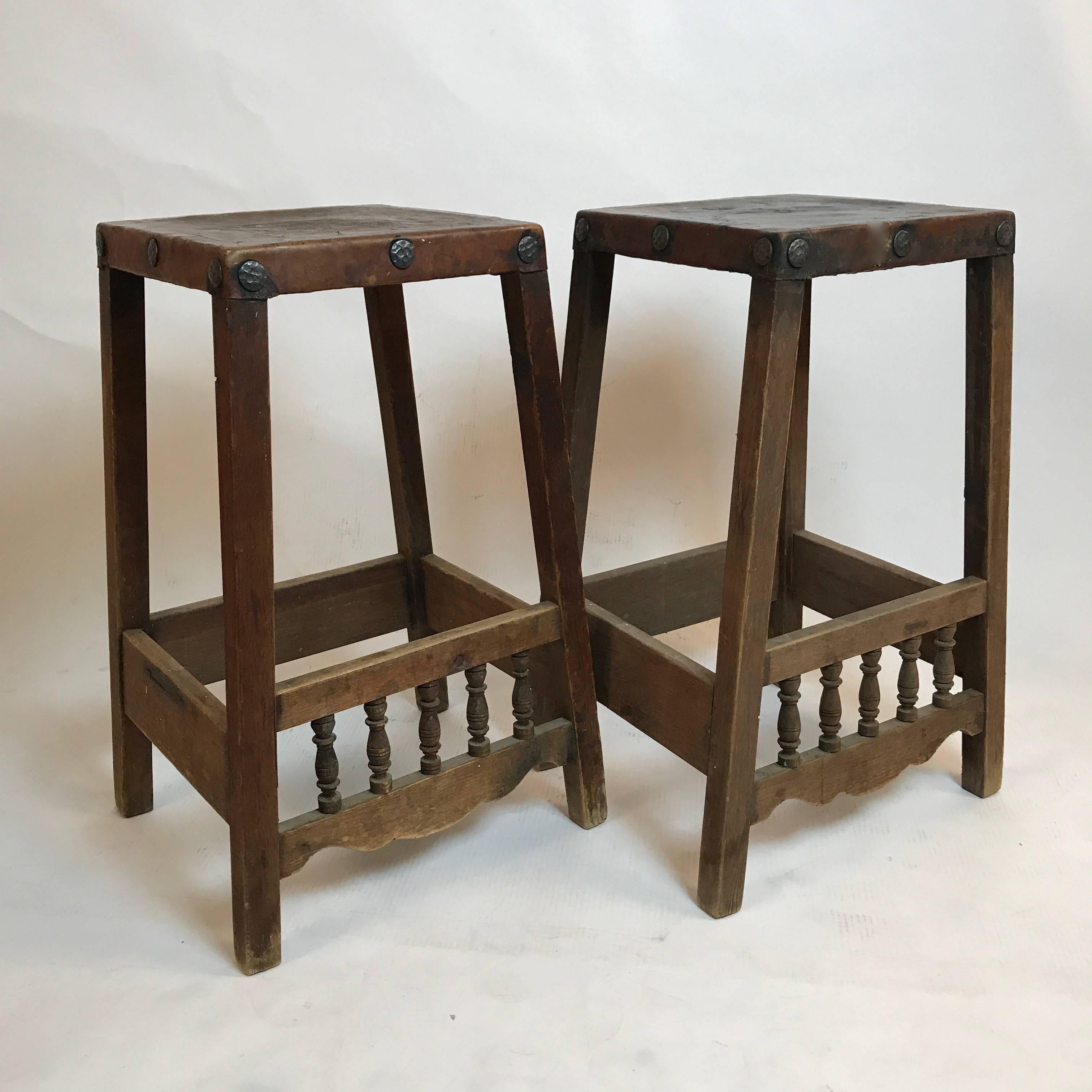 Very unique and solid handmade early American stools constructed of wood with sturdy tanned leather seats that have great patina. Also notice the hand-forged detail on the seat sides. Really great utilitarian stools.