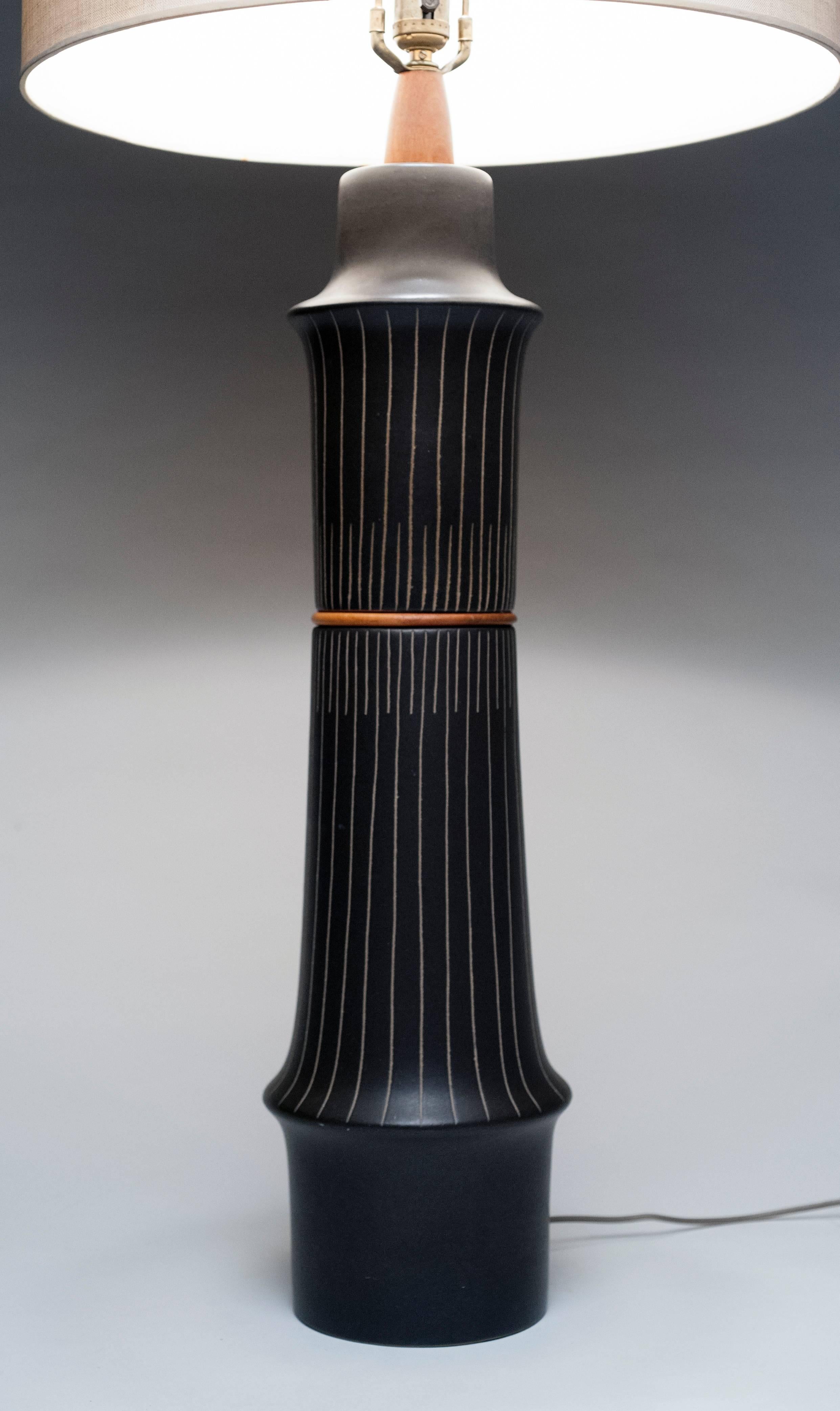 Desirable large ceramic lamp by Jane & Gordon Martz for Marshall Studios. This is a hard to find design in black with striking incised design and walnut accents. Condition is excellent and shade is included. With shade, lamp is 45.75