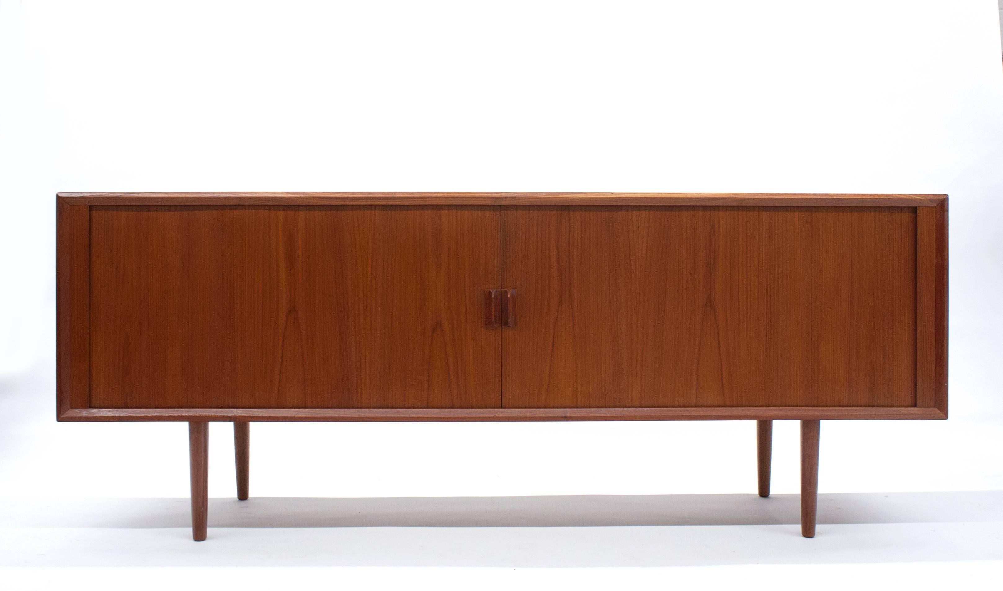 Teak sideboard by Svend Aage Larsen of Denmark. Highly functional with plenty of storage. Three interior shelves are adjustable. Sideboard has been extremely well cared for and is in excellent condition.  Tambour door slides with ease. It's a great