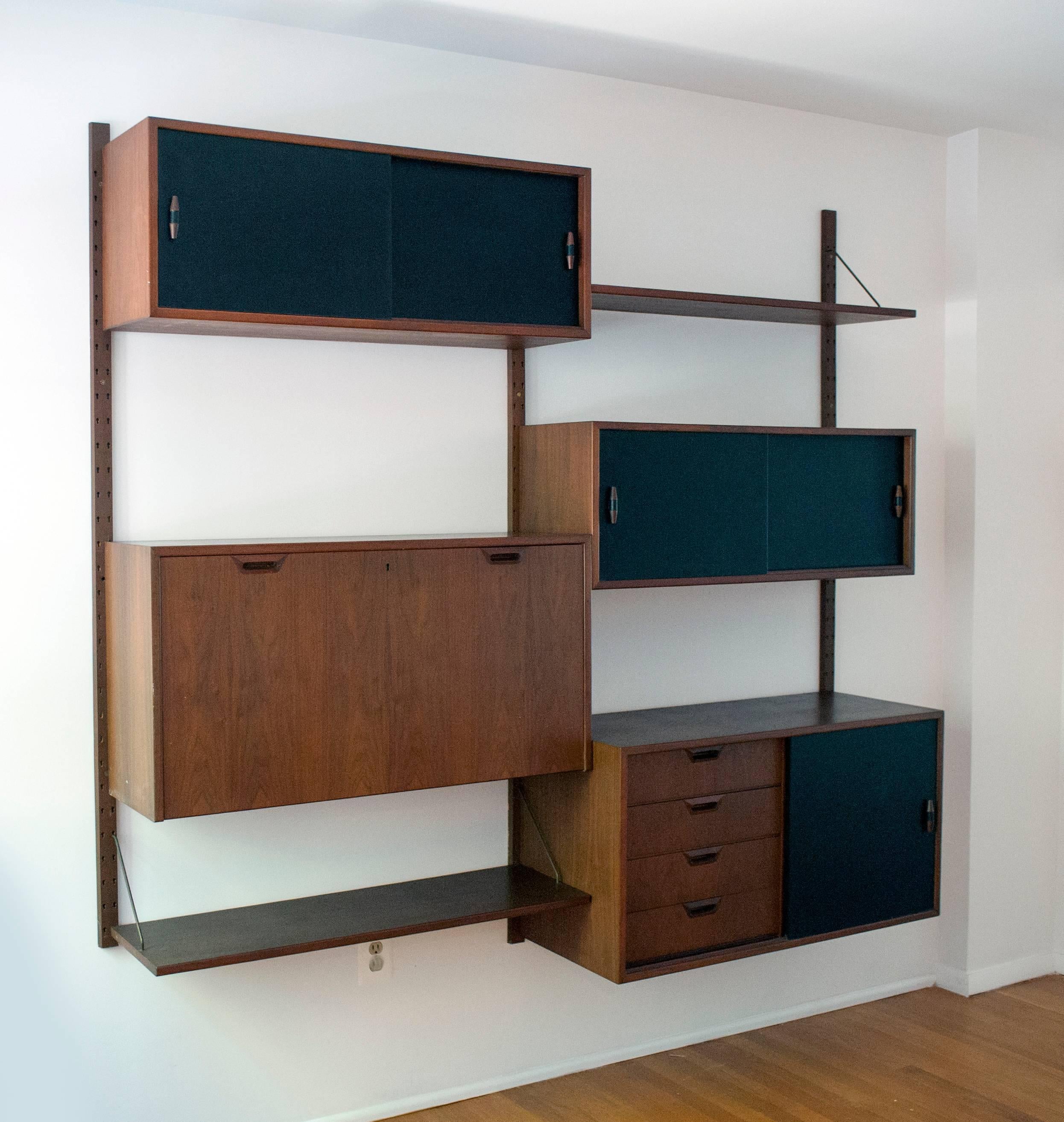 Rarely seen wall unit by Danish designer Sven Ellekaer. Retains the original black sliding doors and unusual pulls. Shelves are supported by solid brass supports. High quality construction throughout. Shelves come with original brass supports. Two