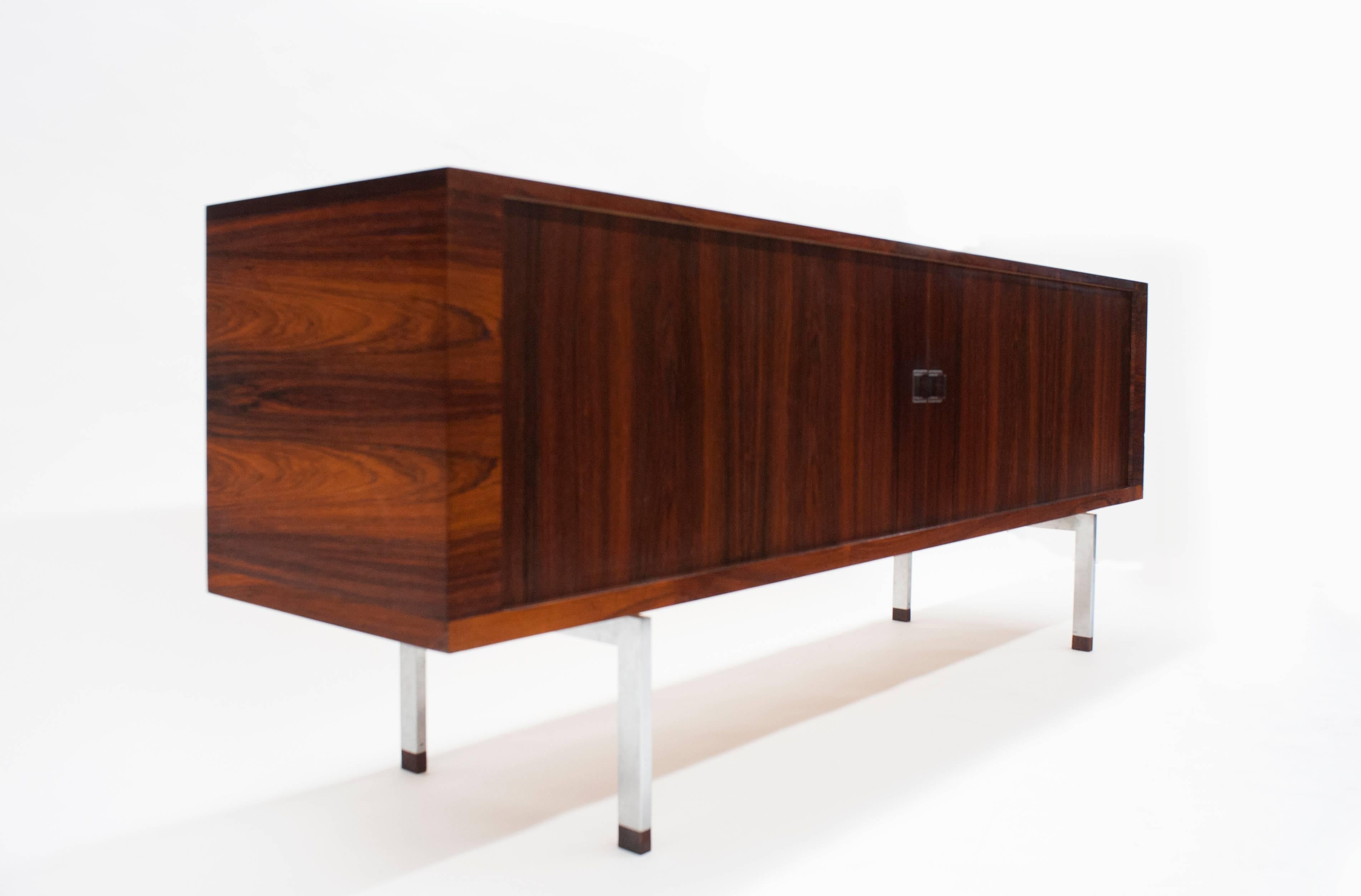 Beautiful Brazilian rosewood sideboard on steel legs by Hans Wegner. Two tambour doors open to reveal spacious oak interior with four adjustable shelves and four sliding trays. Retains the Ry Møbler stamp and 1962 as date of manufacture. Condition