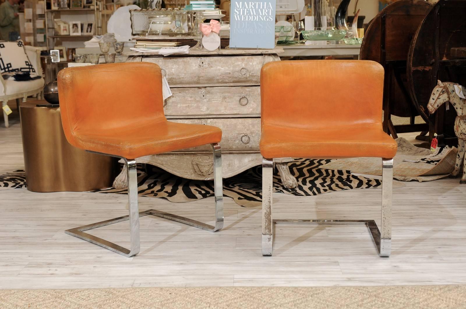 A pair of French Mid-Century chrome and leather chairs from the 1960s. These French desk / accent chairs feature a simple upholstered leather seat over a chrome frame. We can easily picture this Mid-Century Modern French chair in an elegant study,