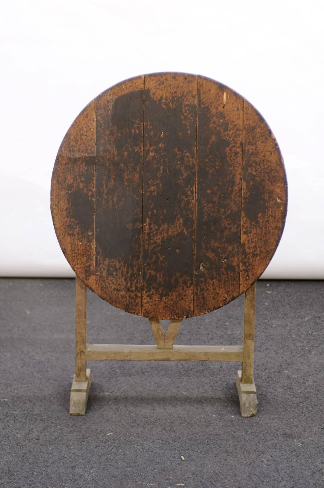 This antique French pine wine tasting table from the late 19th century features a round tilt-top (very slightly oval in fact) over a butterfly wedge trestle base. With its elegant patina and solid build, this rustic and weathered piece will give a