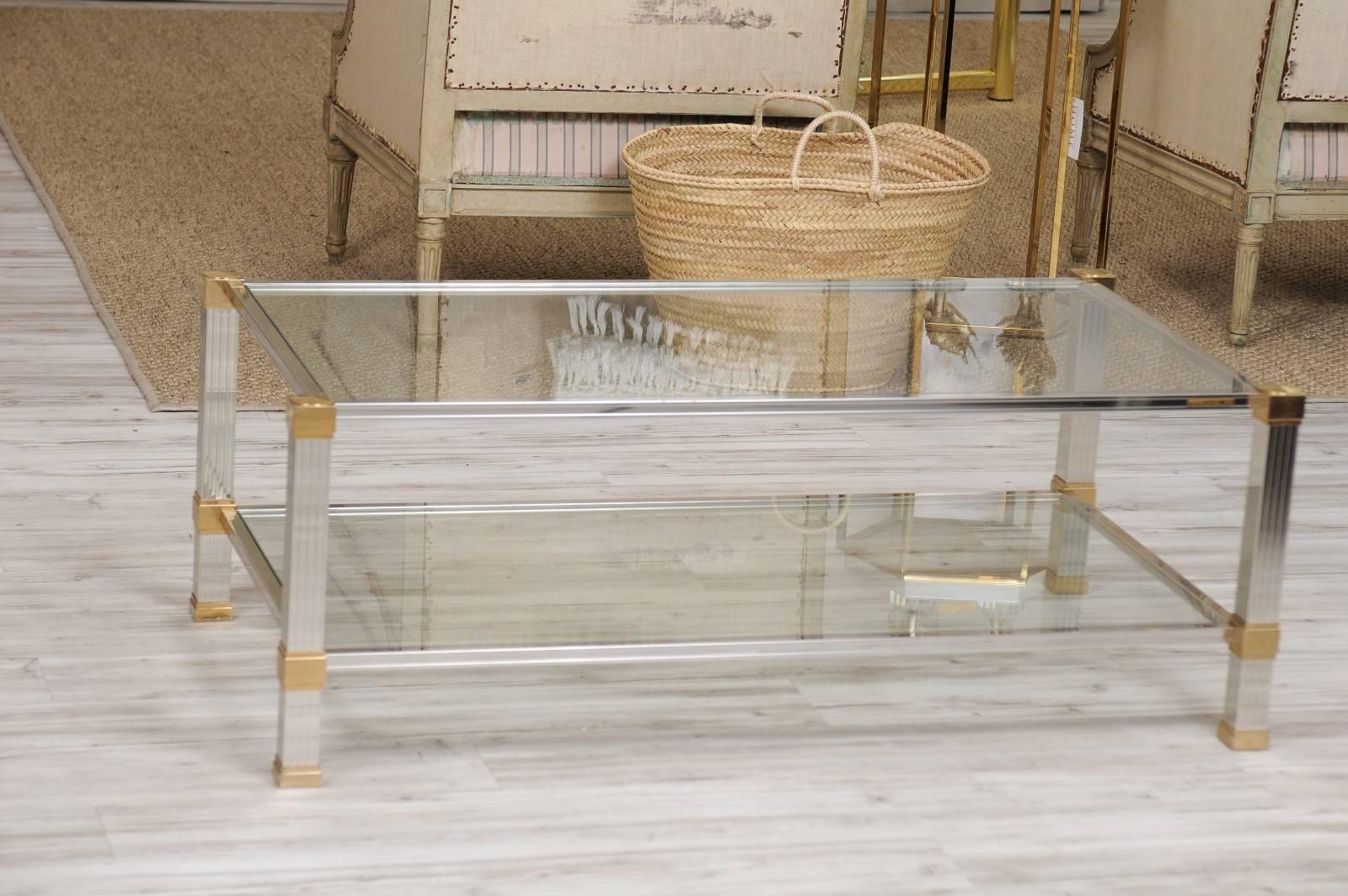 A French Mid-Century Modern brass and chrome coffee table signed Pierre Vandel with linear profile, glass top and lower shelf. The rectangular top and shelf are nicely secured by four reeded chrome legs with brass accents. We’re huge fans of