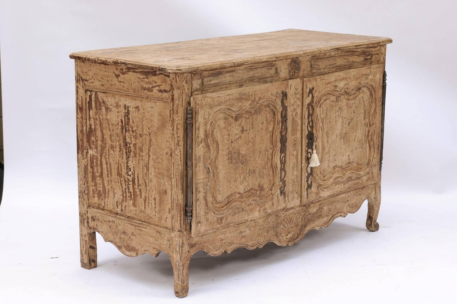 A French stripped wood Louis XV buffet from the Auvergne region of France, from the late 18th century featuring two doors over a carved apron. The rectangular top with rounded corners in the front surmounts a set of double doors opening up to reveal