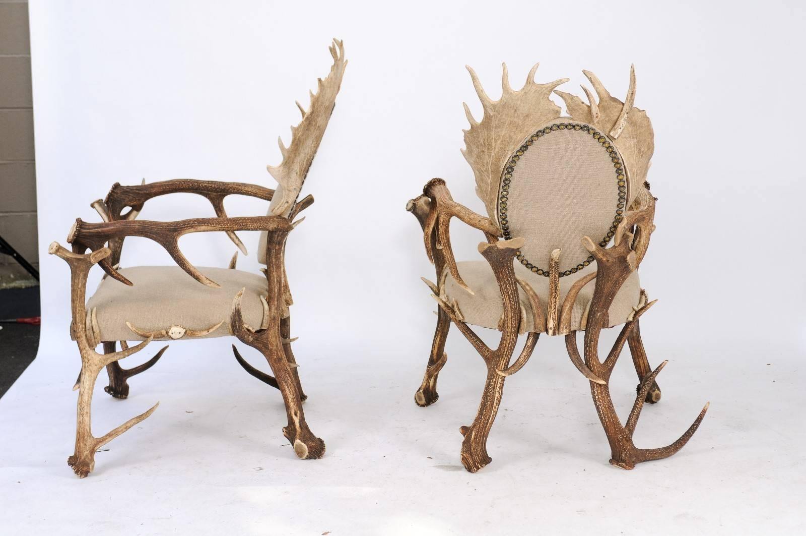 Pair of French authentic antler built armchairs, upholstered in linen with oval backs flanked by striking moose antlers. When we realized the artistic craft involved in making a pair of armchairs with all natural antlers that were as handsome as