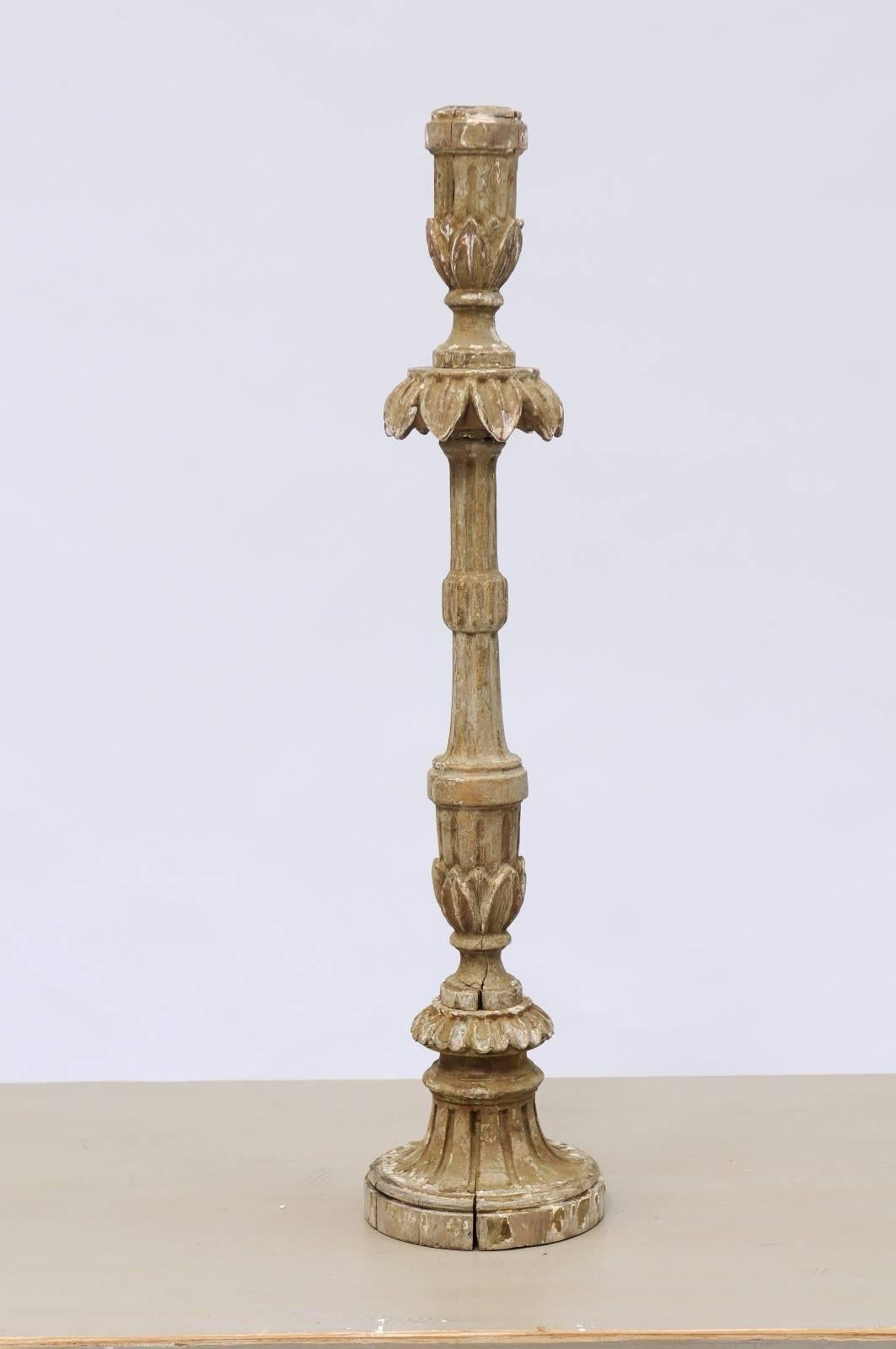 A tall 18th century Portuguese carved wood candlestick with foliage motifs and fluted body. With its elegant floral motifs, gorgeous patina and striking size, this 18th century Portuguese candlestick will elevate any space with its exquisite