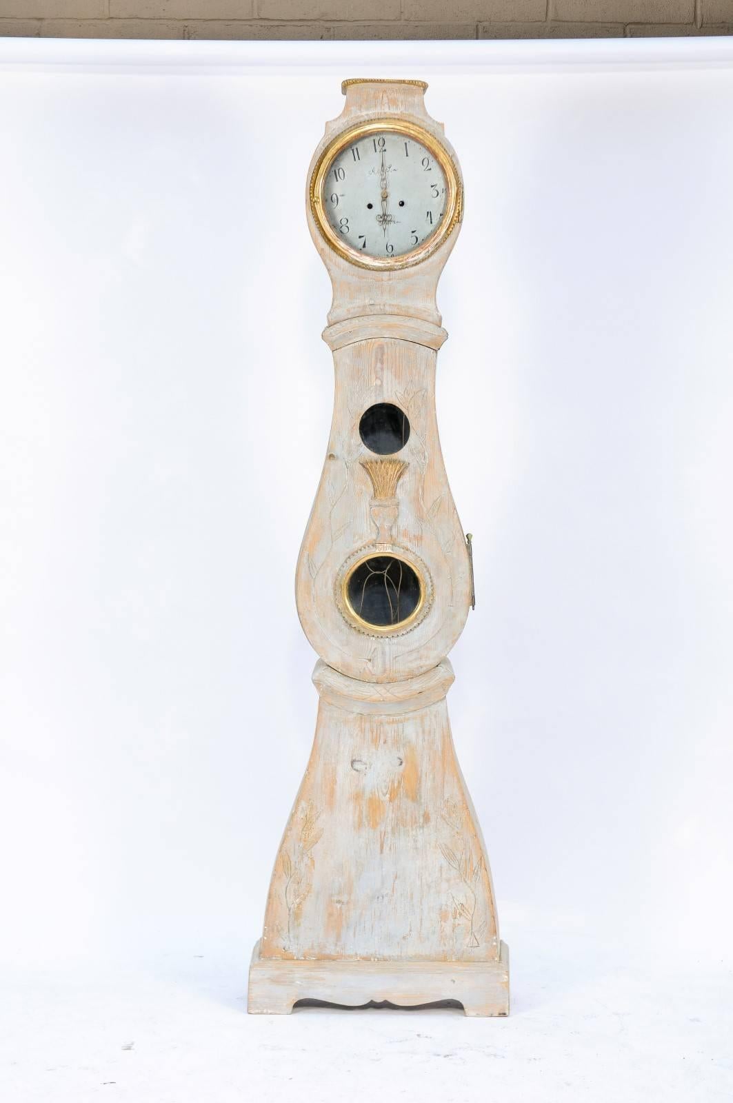 A Swedish painted wooden Mora clock from the mid-19th century with gilded accents. We fell in love with this charming piece at an antiques fair in France. With its sophisticated patina, neat lines, a rounded head and “belly” and an elegant clock