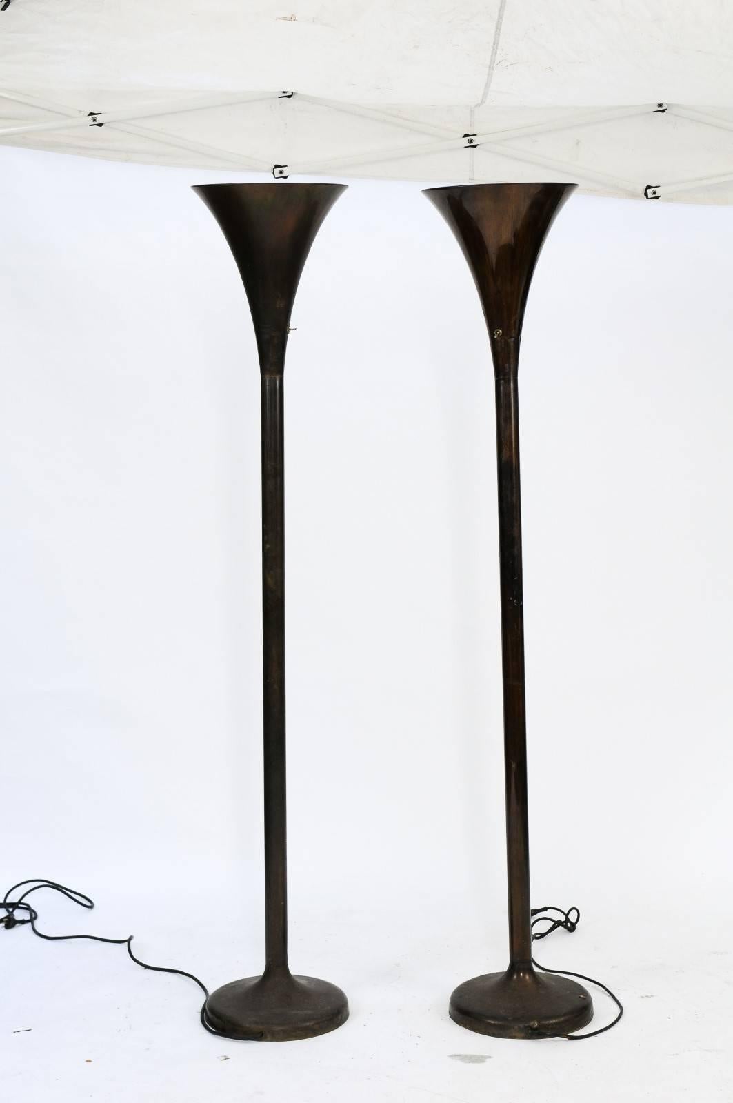 A pair of French black metal torchères floor lamps from the mid-20th century. This pair of 1950s metal torchère lamps had us at the switch! We immediately fell in love with the patina of the metal and the graceful shape and size of the lamps. We can