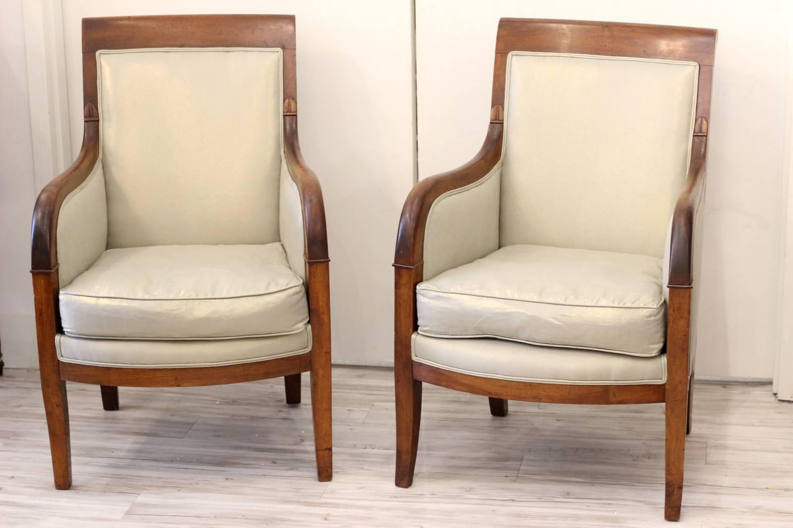 A pair of Northern French Empire style walnut and linen upholstered bergères with rolled arms from the mid-19th century. We fell in love with the beautiful antique French walnut on this pair of Empire style bergeres armchairs that we found in