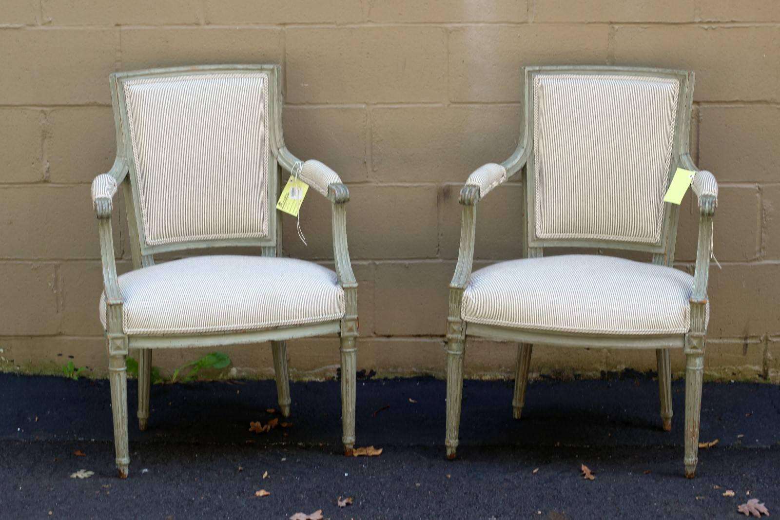 Pair of 1920s French Louis XVI style painted armchairs with double welt cotton upholstery, scrolled arms, square backs and fluted legs. We love the stately and classic lines of these impressive, Louis XVI-inspired square-backed chairs, painted in a