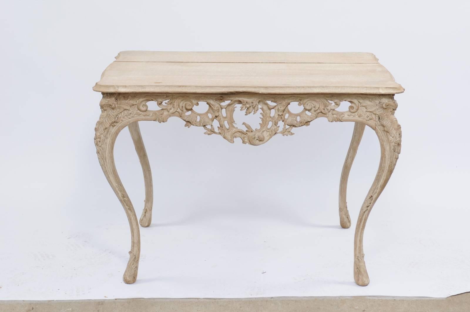 A French 19th century stripped oak Louis XV style side table with beveled top, exquisitely carved apron with rocailles motifs and tall cabriole legs. Finding this table was an Aha moment for us. First off, it is stunning in every way: the